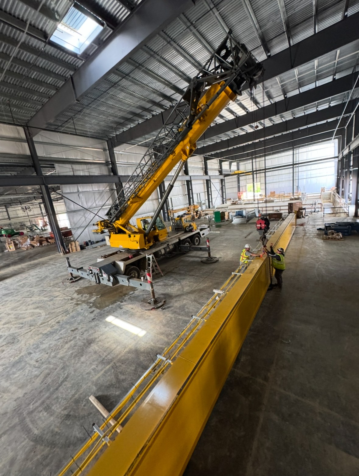 A bridge girder staged on the floor alongside the mobile crane and installation crew.