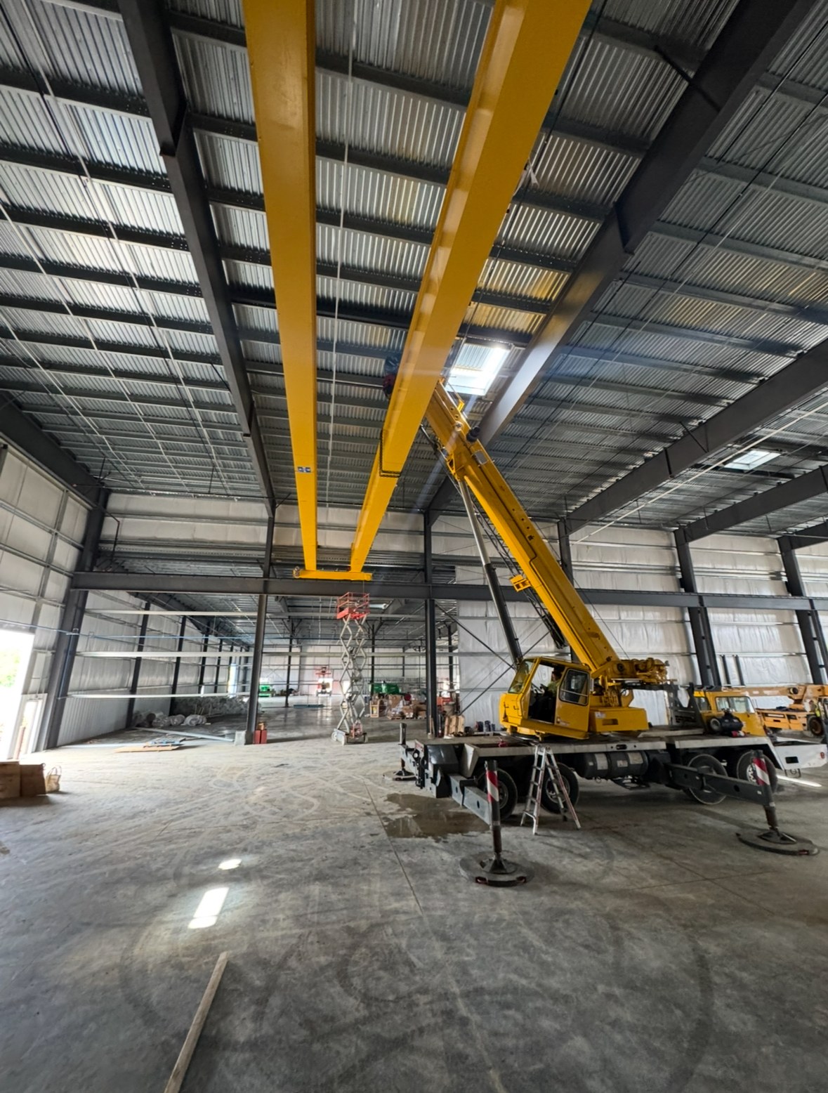 Both bridge girders viewed along their length above the mobile crane and scissor lift.