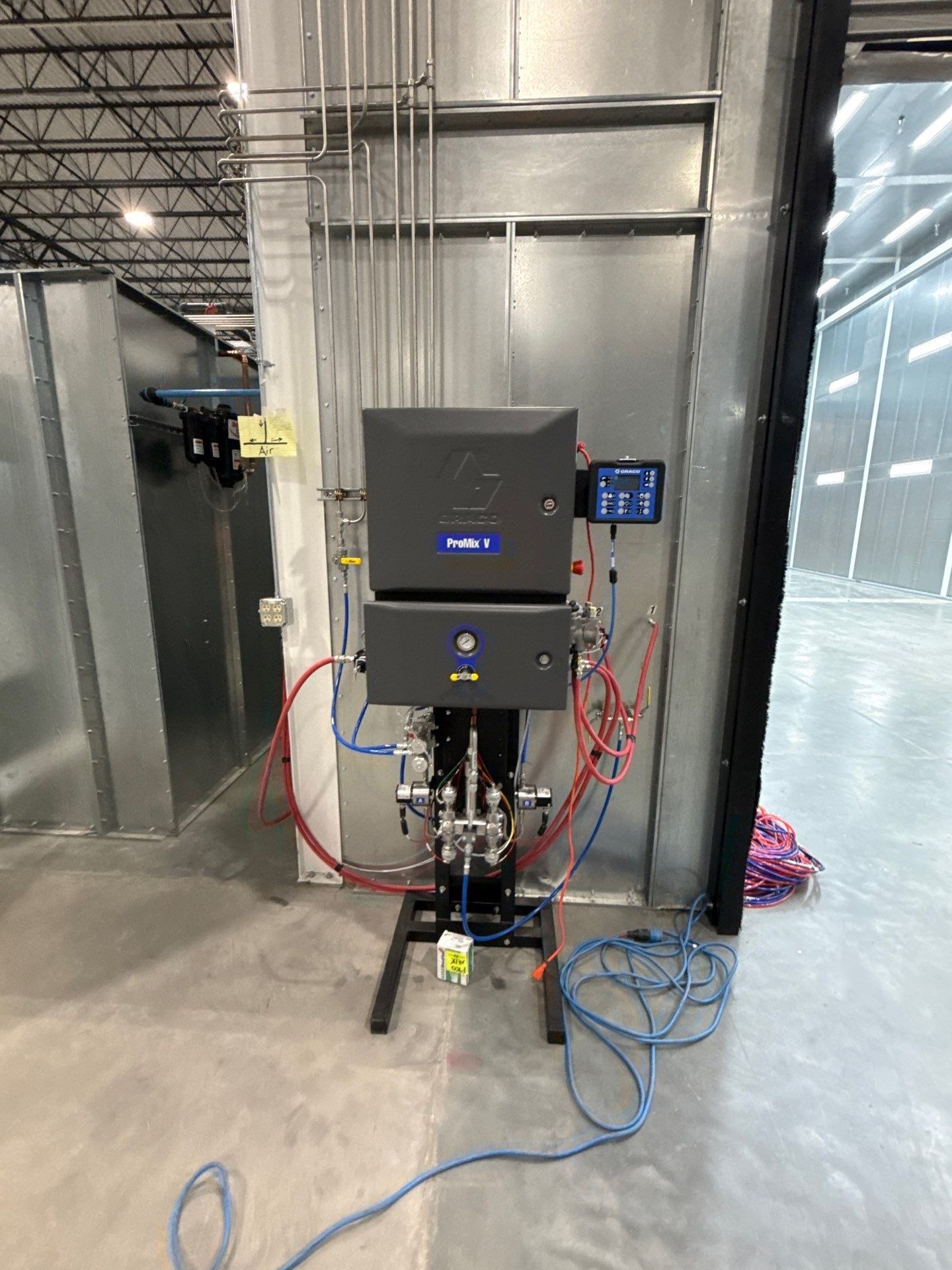 Paint proportioning equipment and connected hoses at the booth entrance.