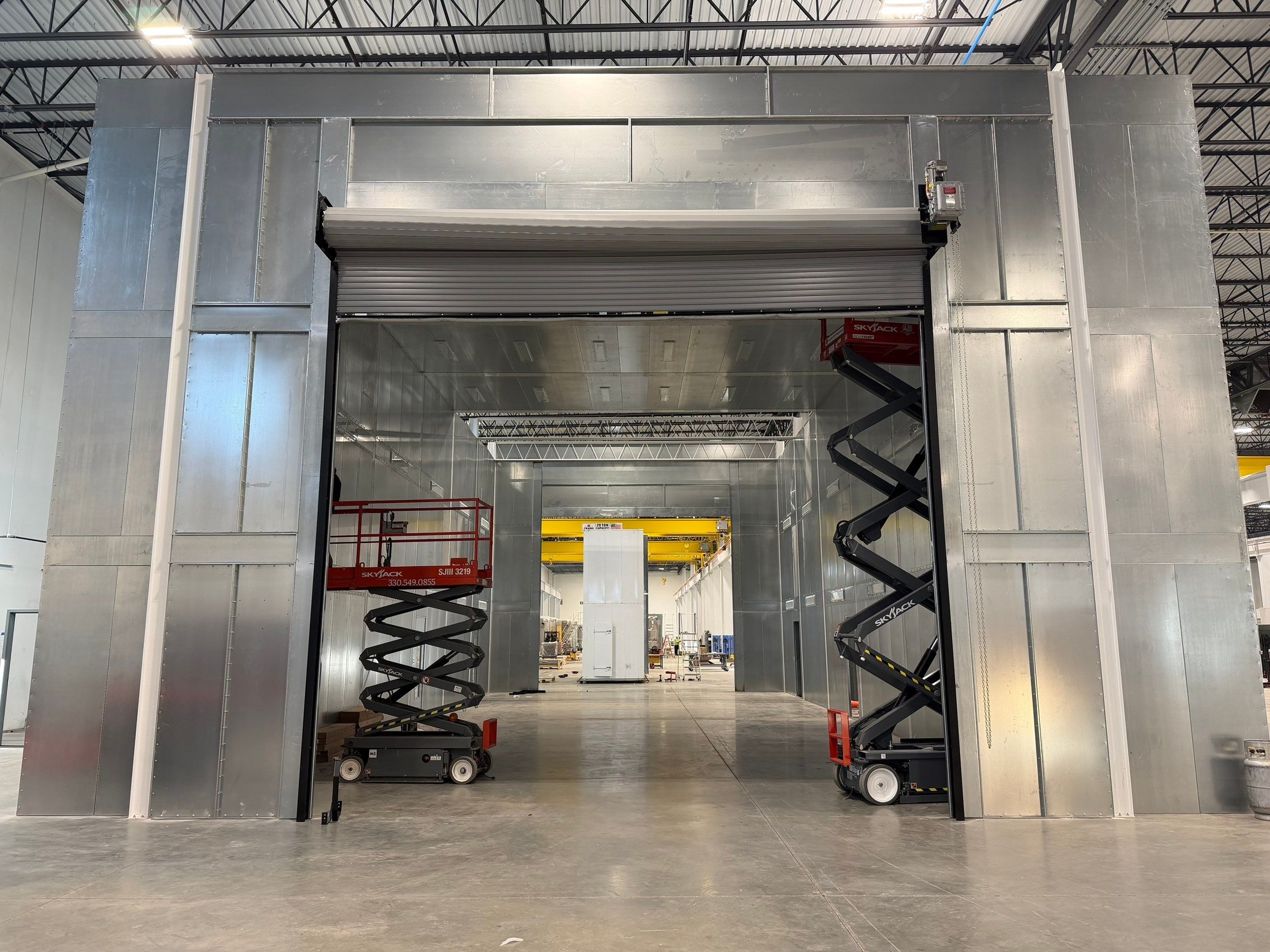 Front view of the booth enclosure and roll-up door with installation lifts inside.