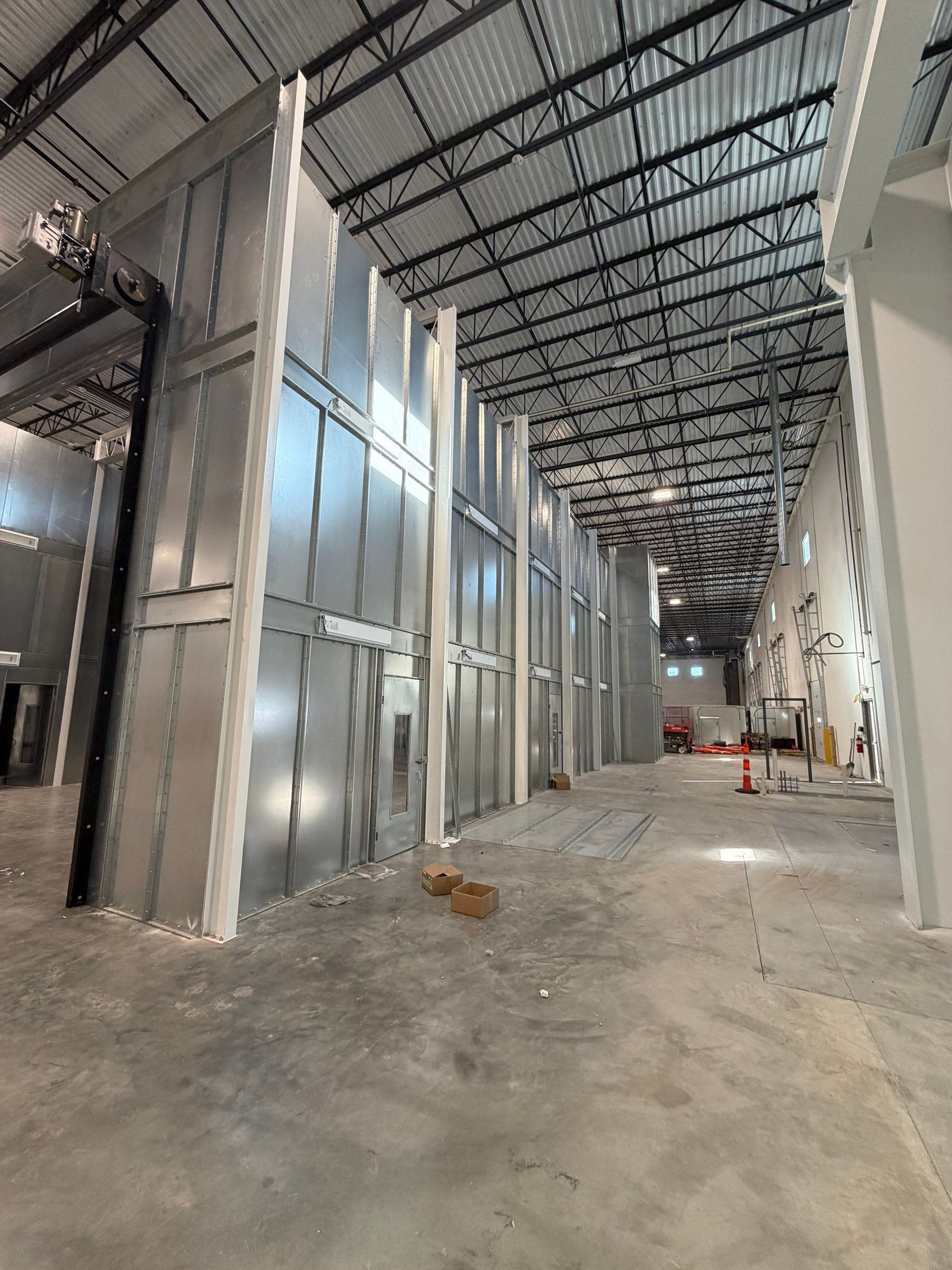Long view along the booth sidewall, personnel doors, and surrounding installation aisle.