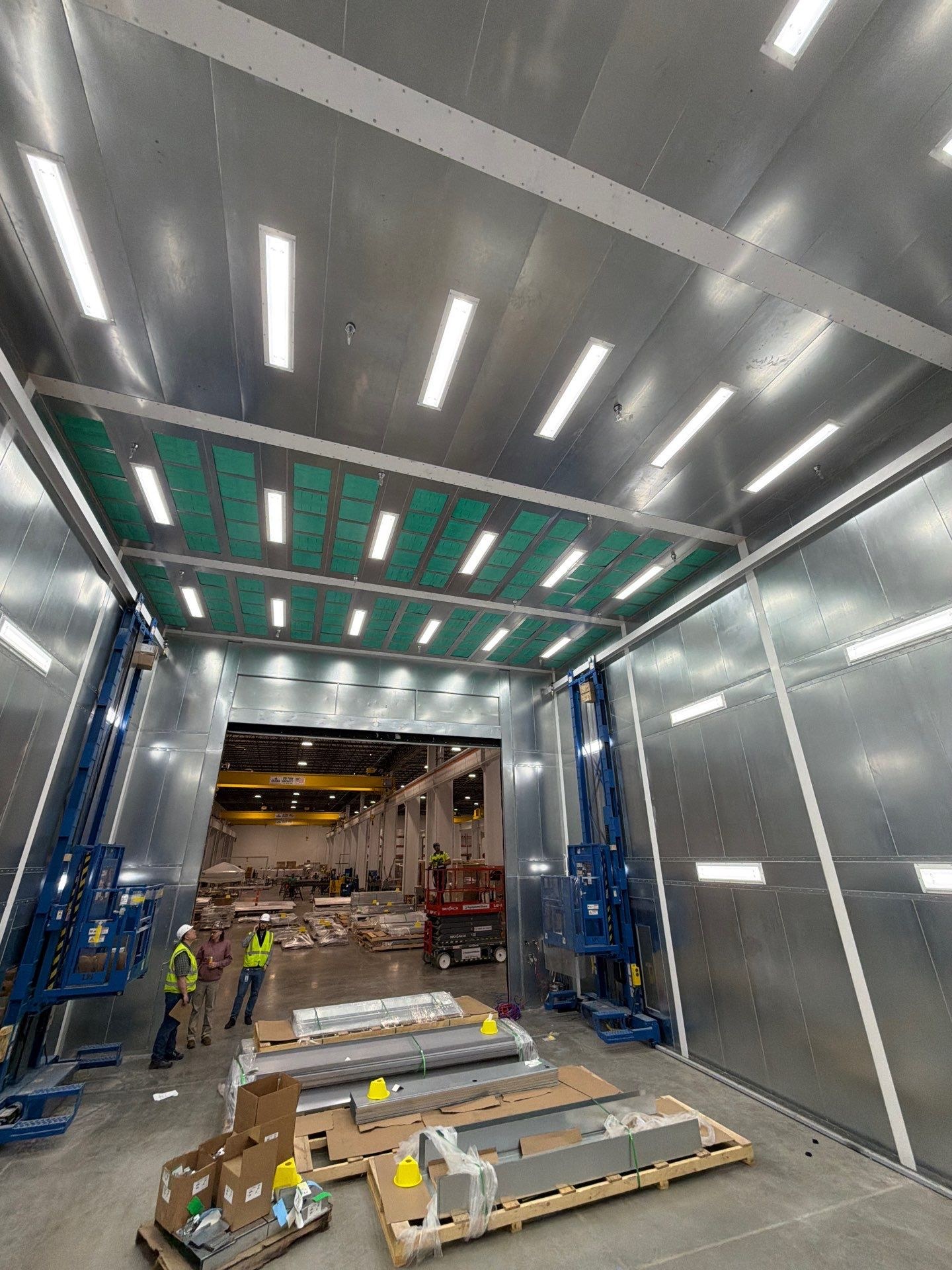 Late-stage installation inside the illuminated booth, with man lifts and remaining materials.