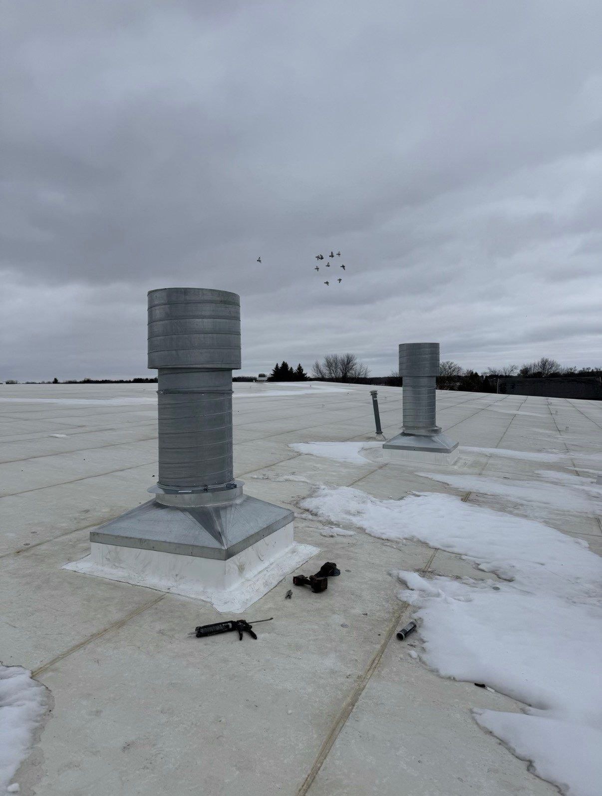 Two rooftop exhaust stacks and their curb connections during installation.