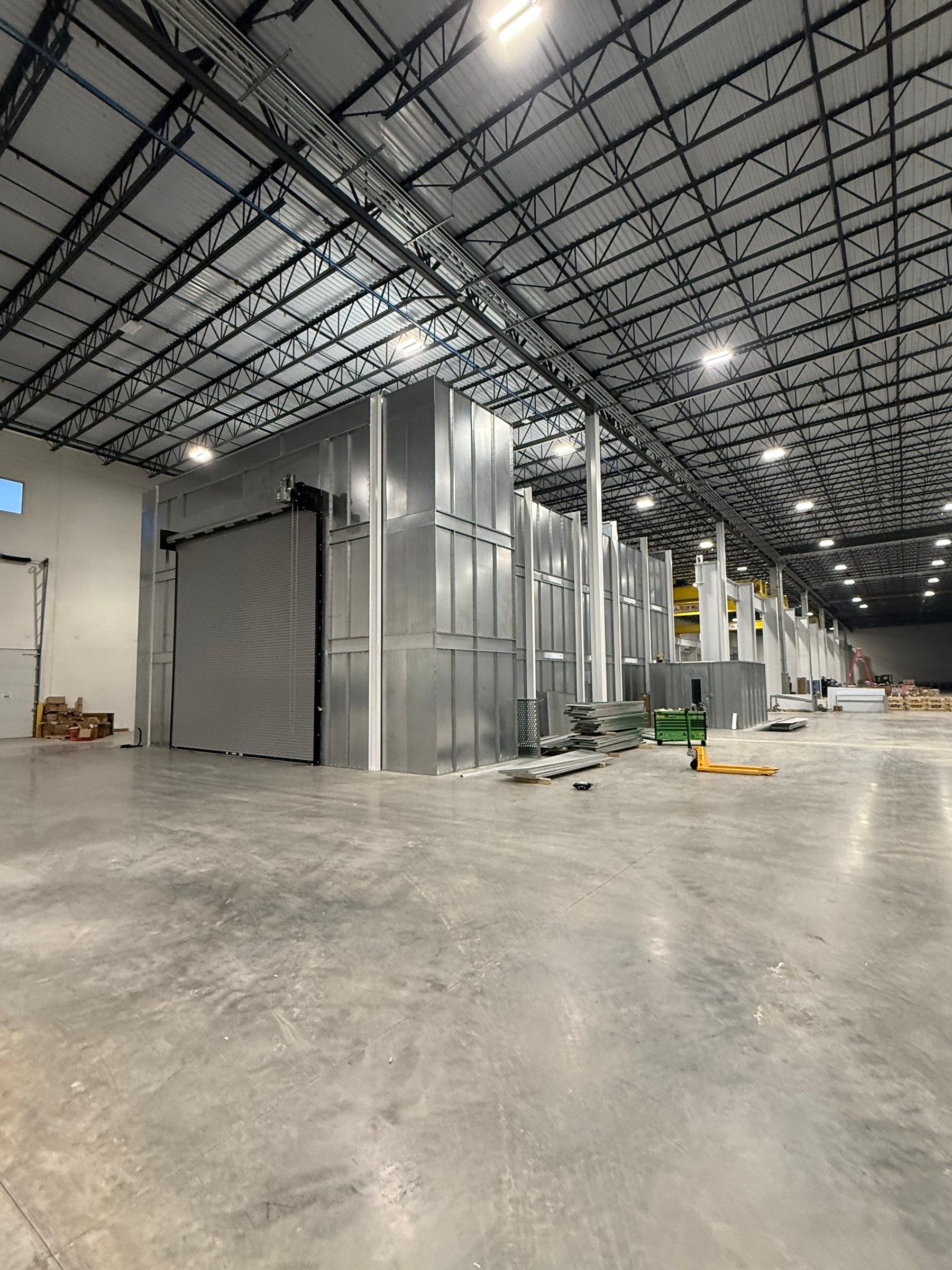 Wide exterior view of the spray booth with its roll-up door closed.