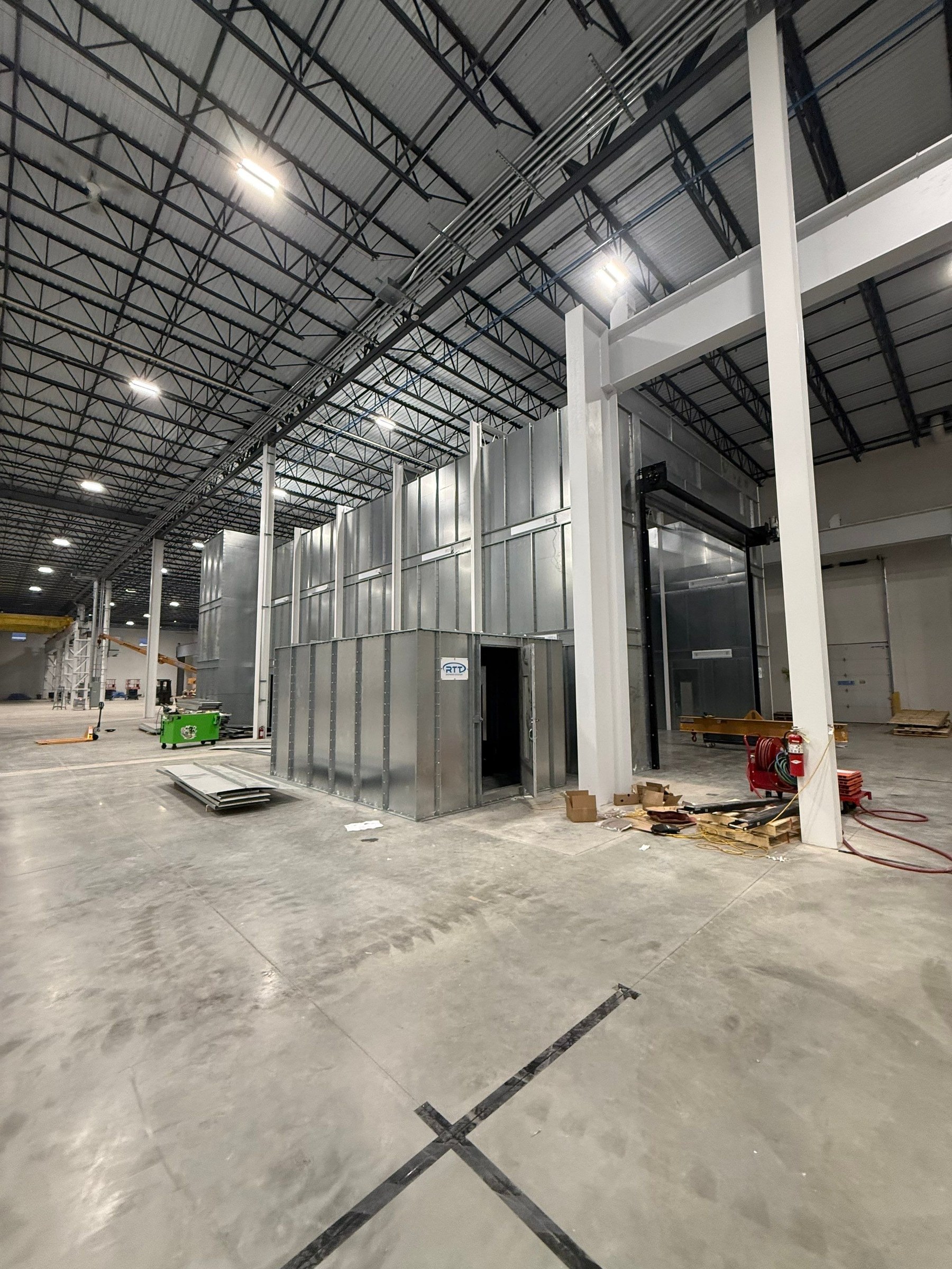 Mix-room enclosure beside the spray booth entrance, showing its personnel door and surrounding plant aisle.