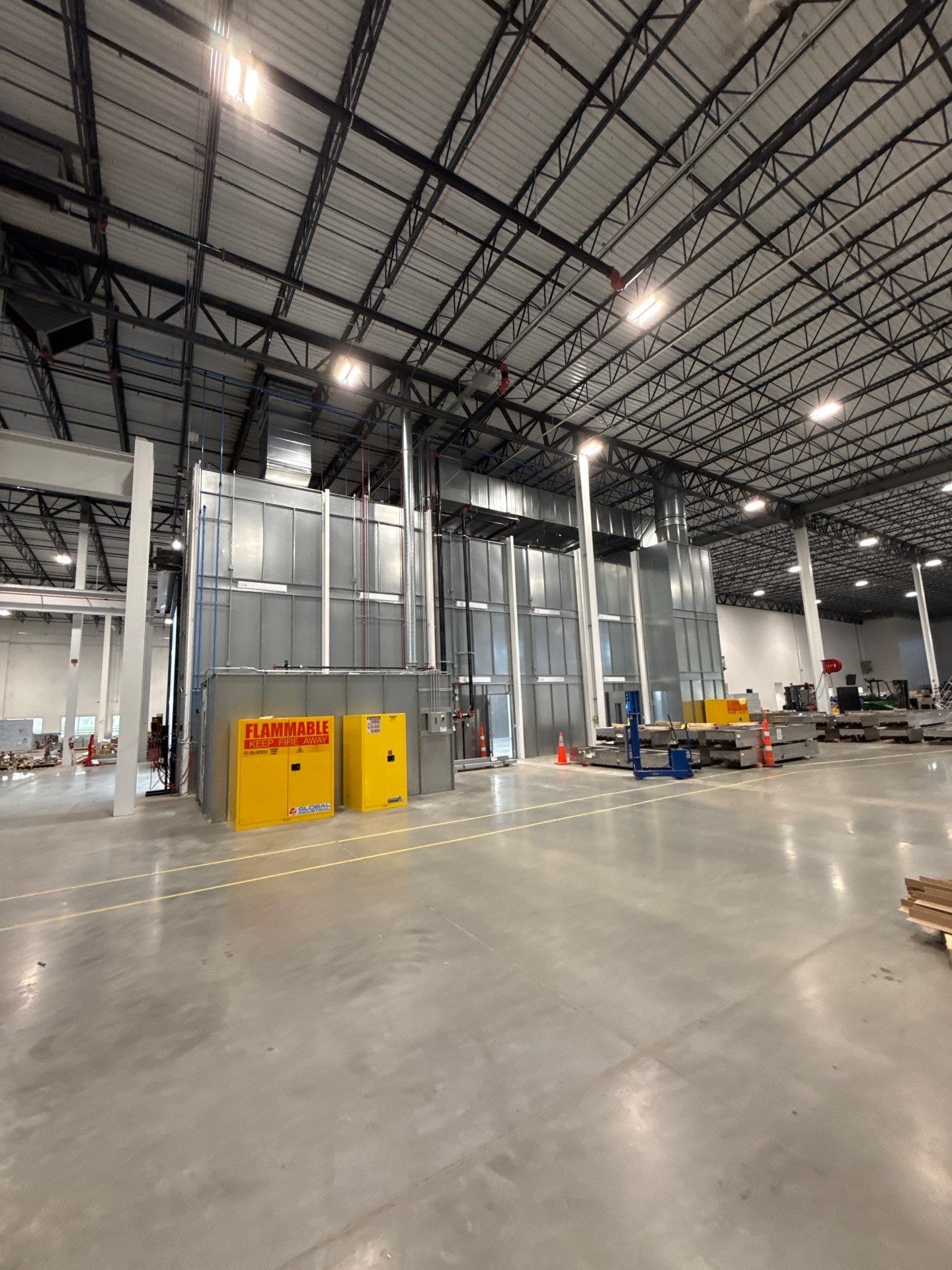 Wide view of the booth sidewall, overhead ductwork, connected utilities, and mix-room storage cabinets.