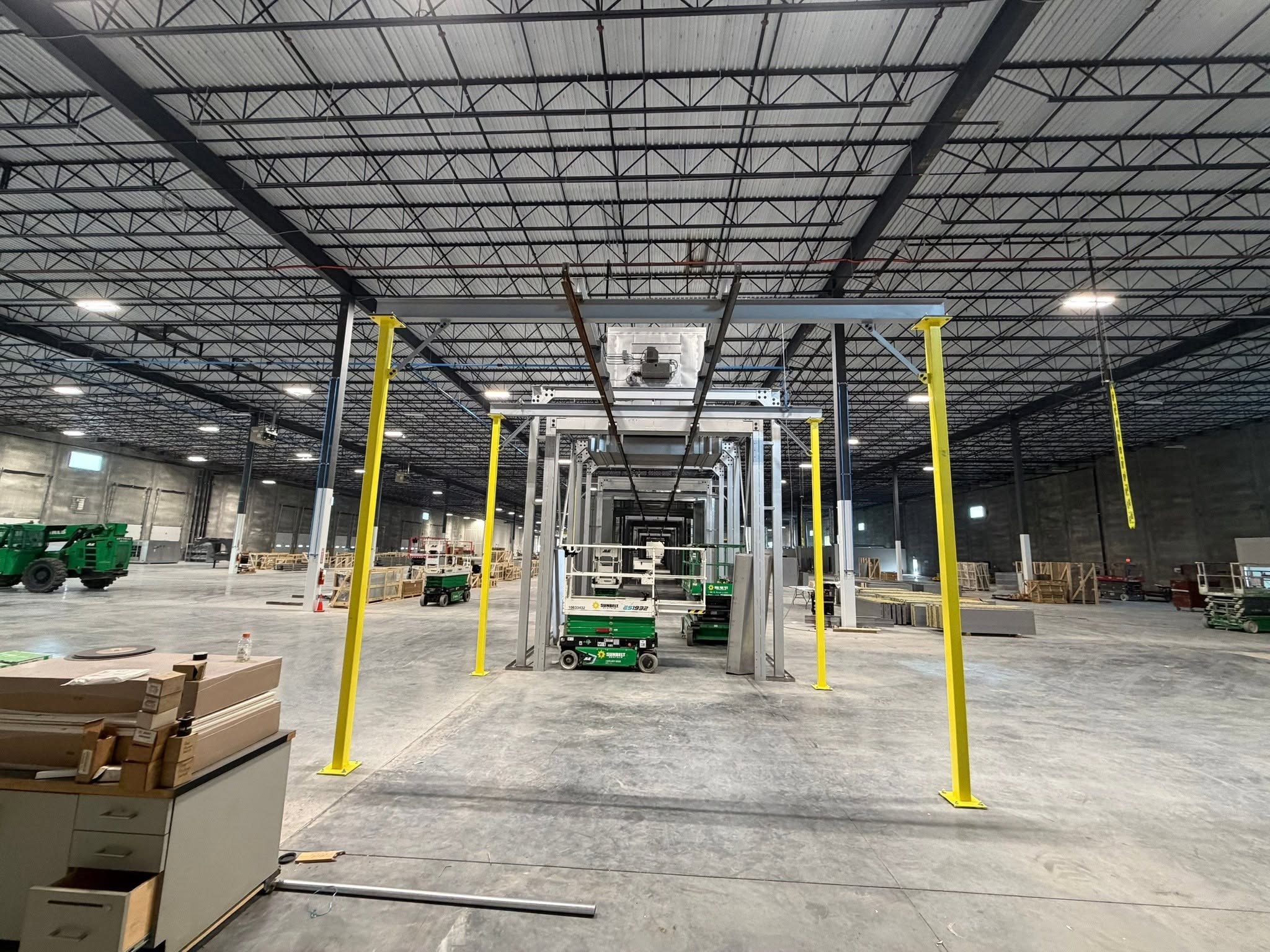 Front view of the dual-rail conveyor and yellow support columns in the powder-coating installation area.