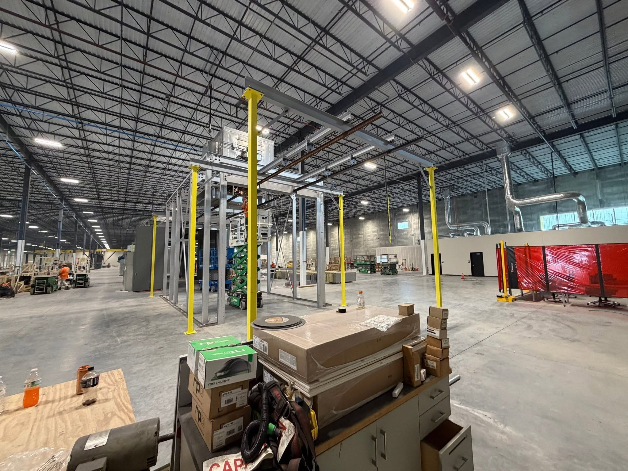 Dual conveyor rails, crossmembers, and yellow columns alongside the finishing equipment.