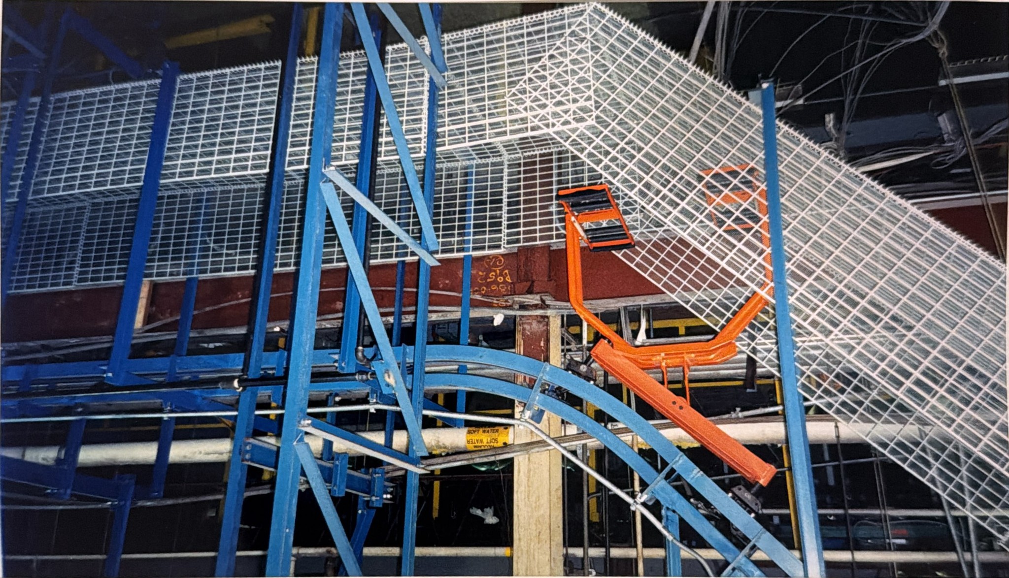 An orange carrier beneath the curved overhead track at an elevation transition.