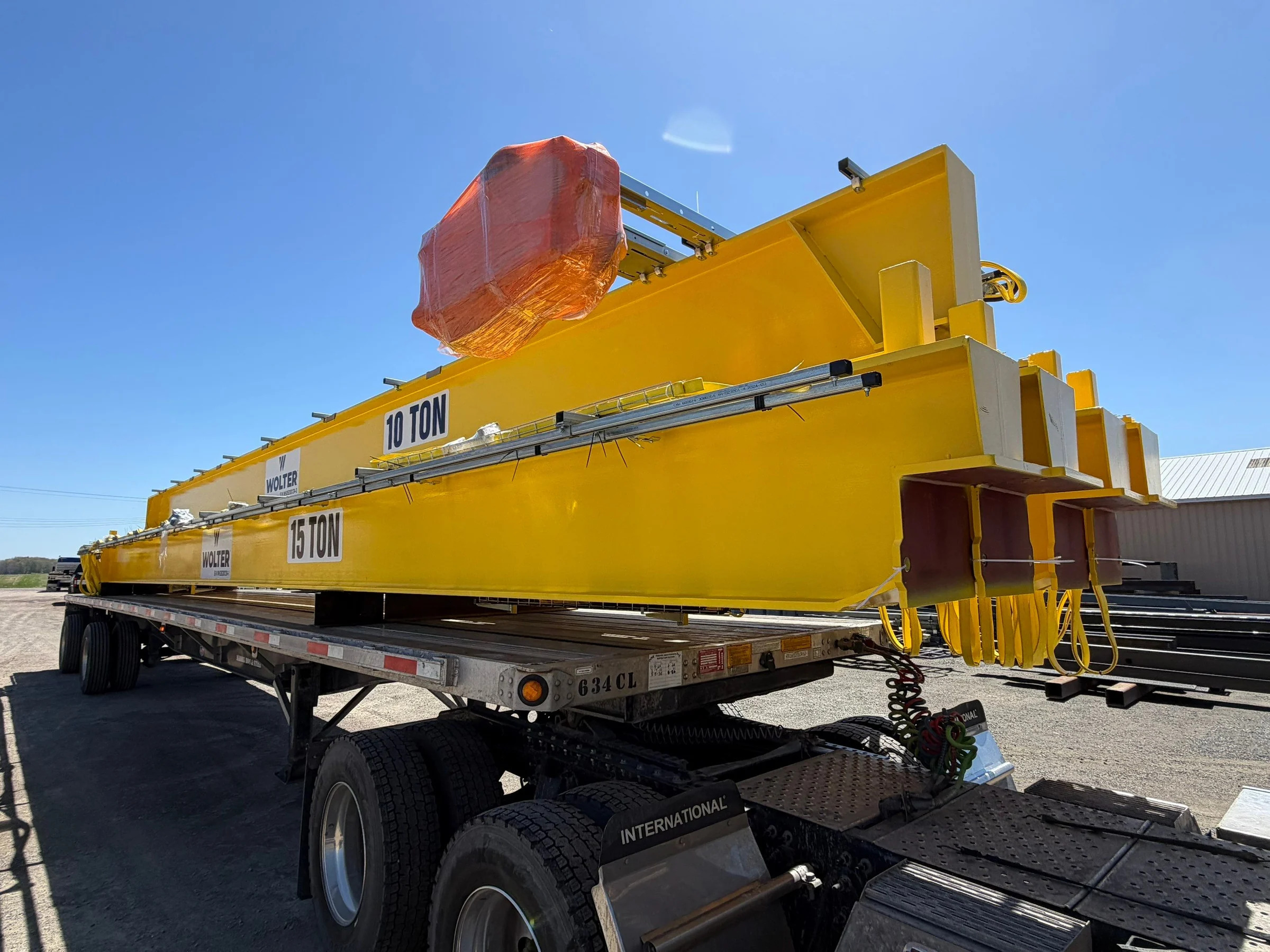 New yellow Wolter-branded bridge crane equipment marked 10 ton and 15 ton on a delivery trailer