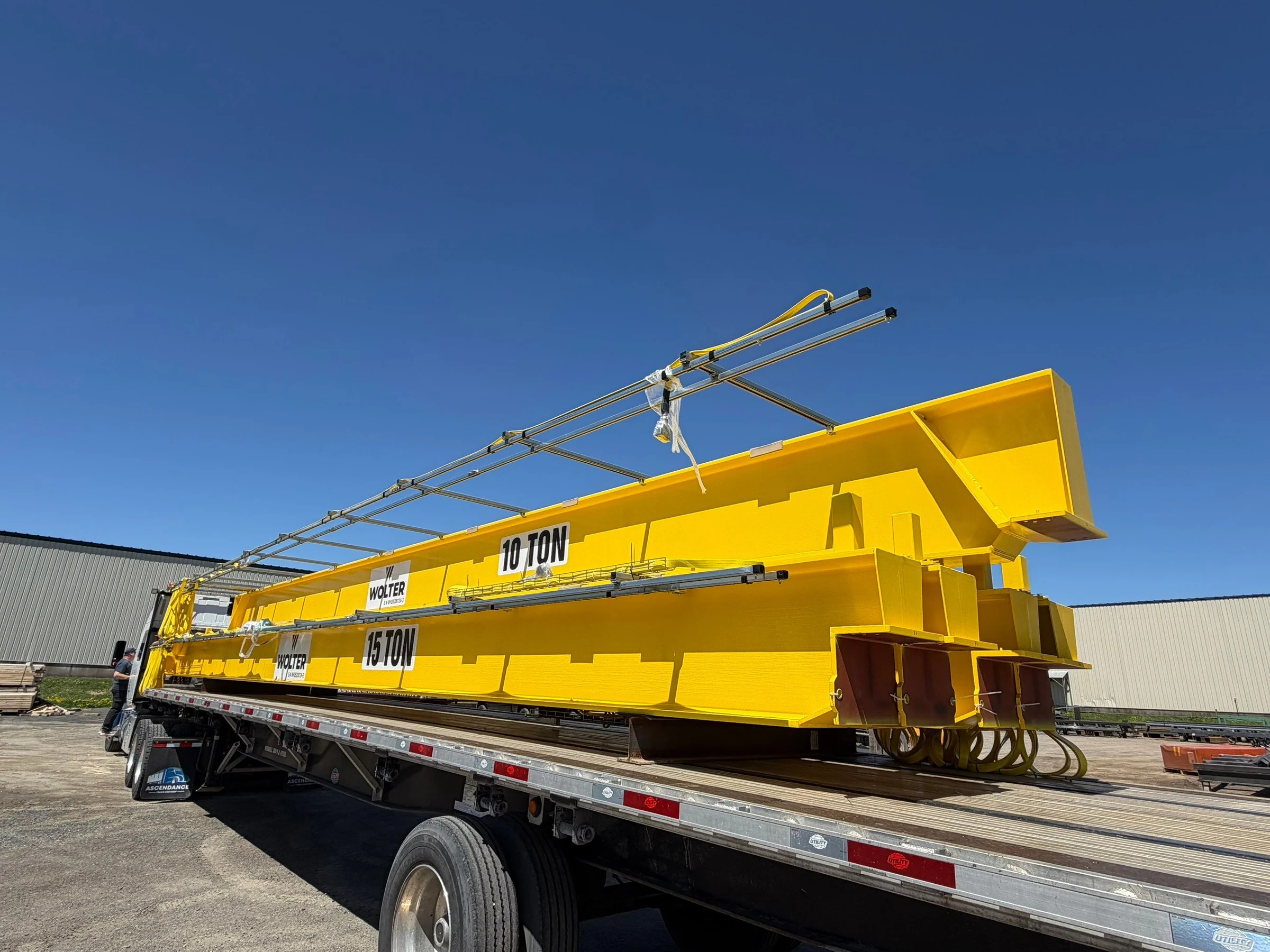 Replacement 10-ton and 15-ton bridge girders with electrical equipment on a flatbed outside the facility