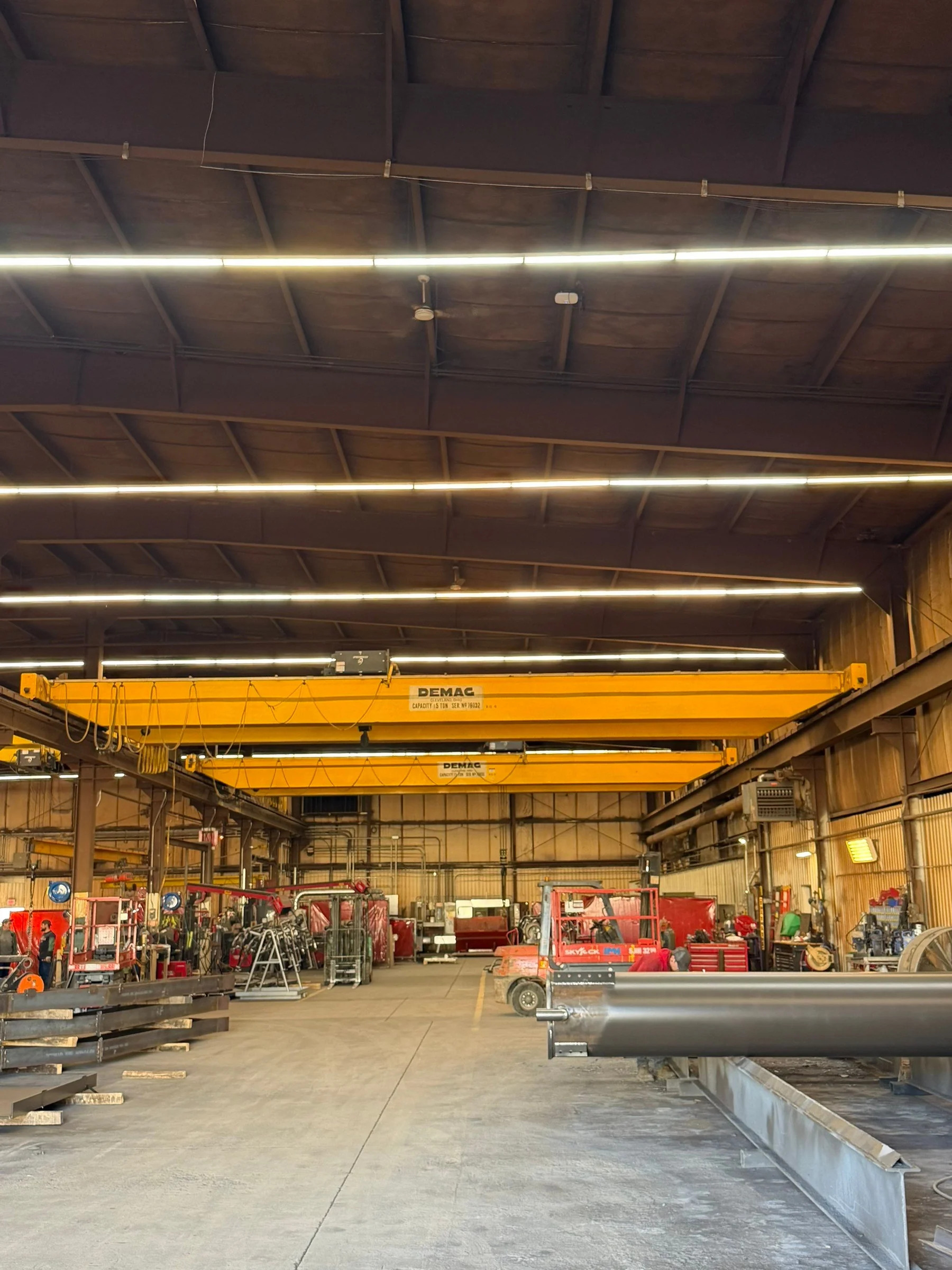 Two old yellow Demag bridge cranes above the fabrication floor before removal at Lejeune in Thorp, Wisconsin