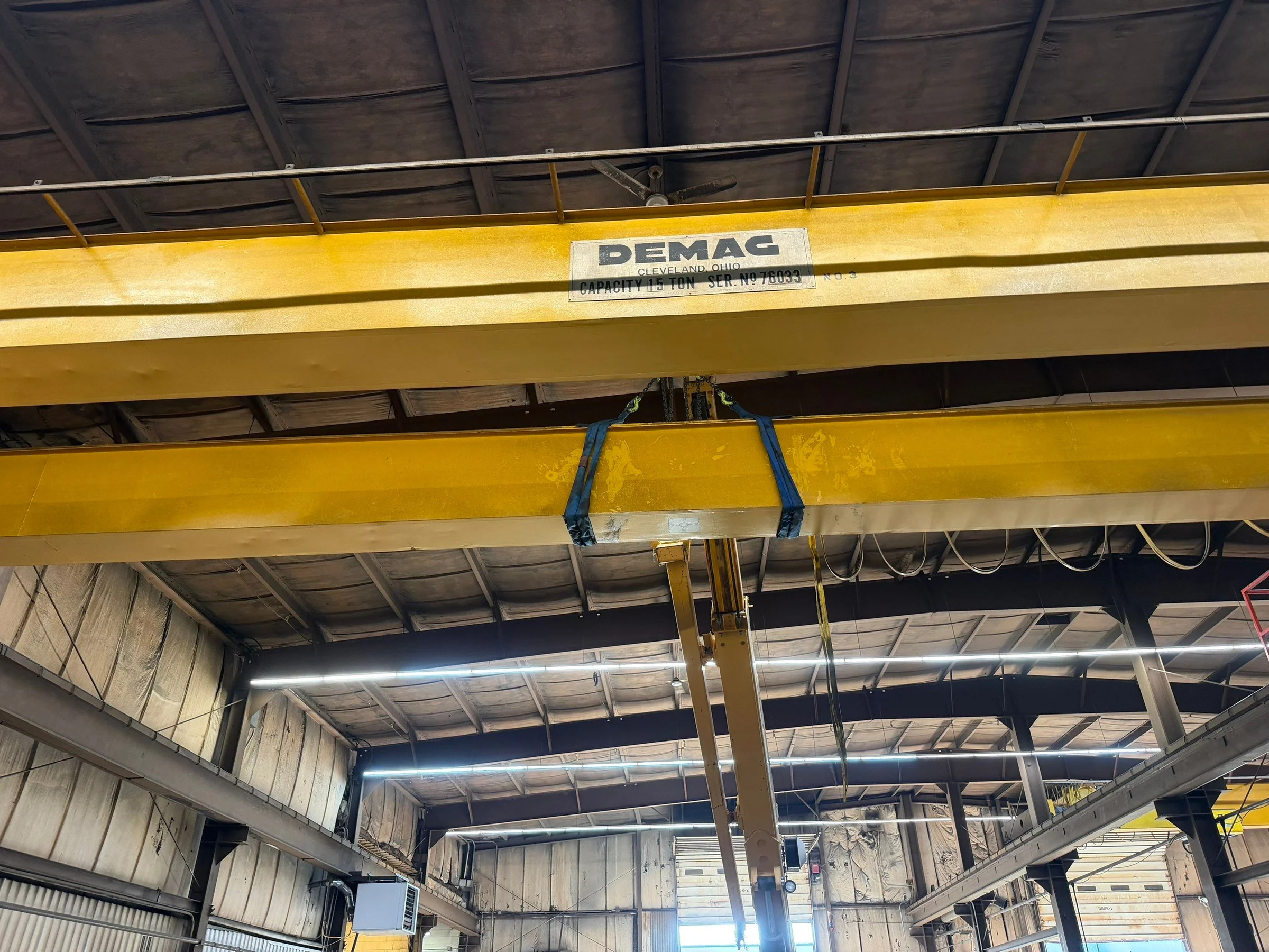 Blue slings around an old bridge girder with the mobile crane boom below