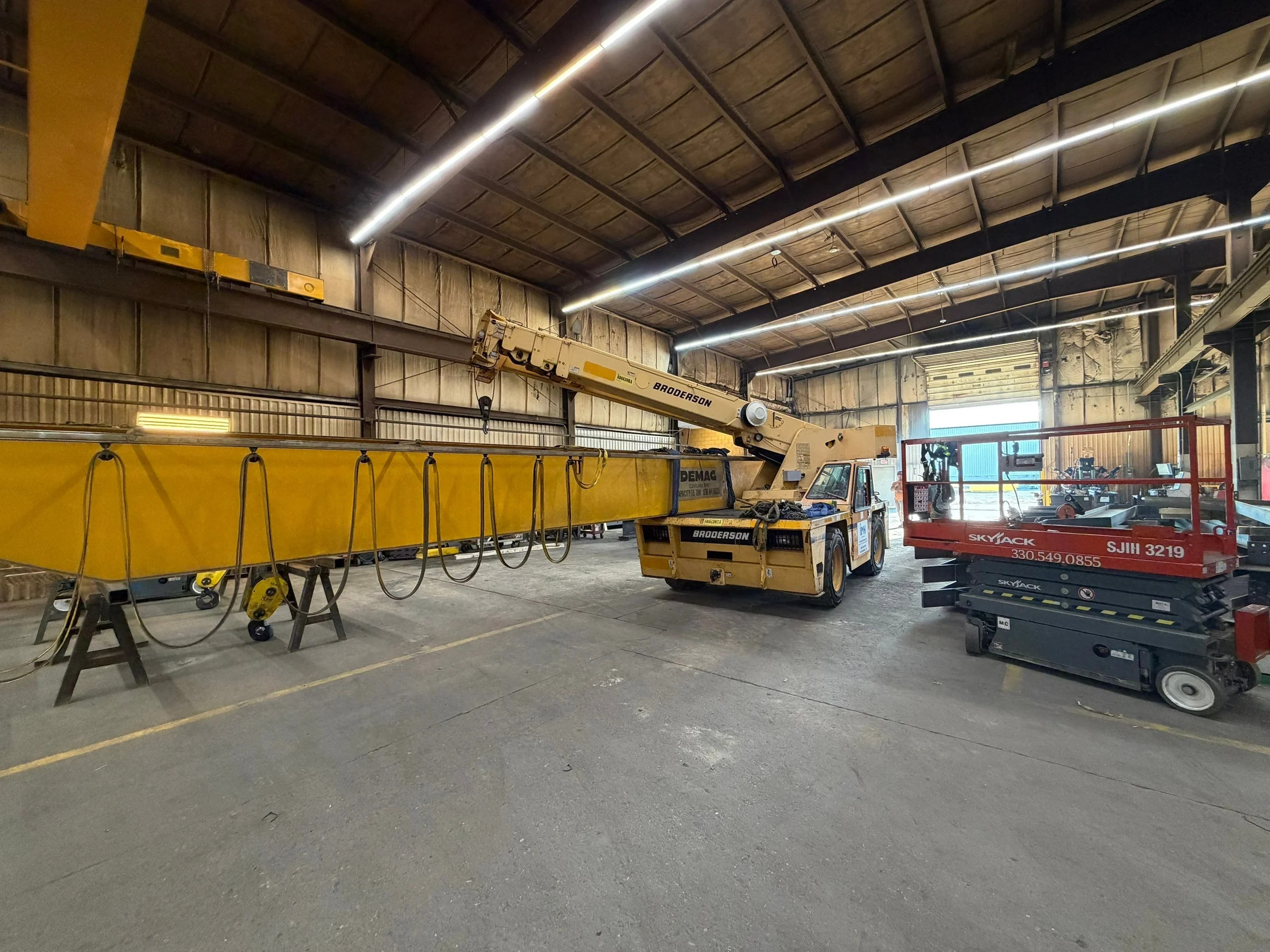 Lowered old bridge girder, mobile crane, and red access lift on the Lejeune shop floor