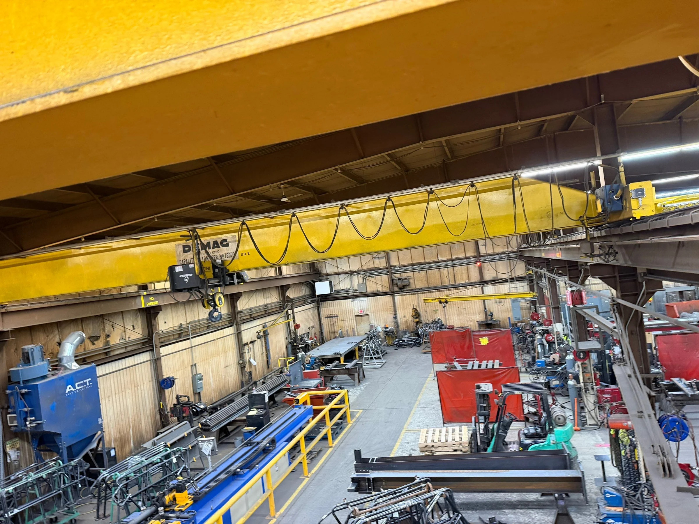 Existing yellow bridge crane, hoist, and festoon cables viewed from runway height