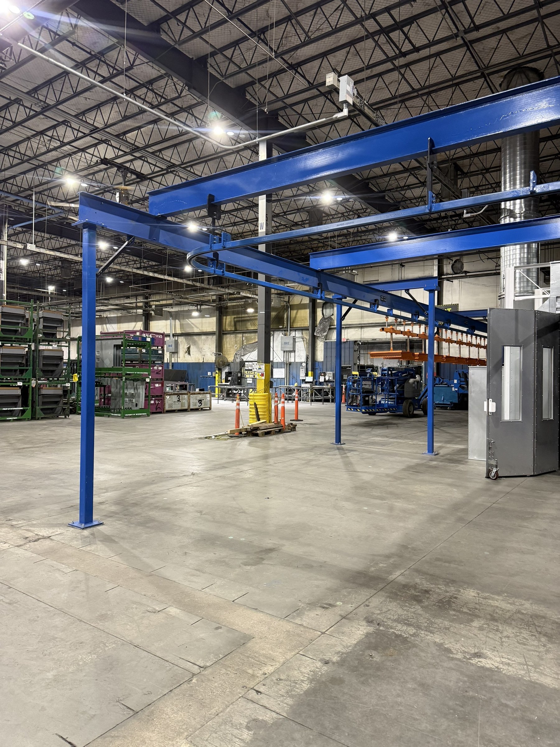 Overall view of the blue support steel and overhead conveyor route around the booth.
