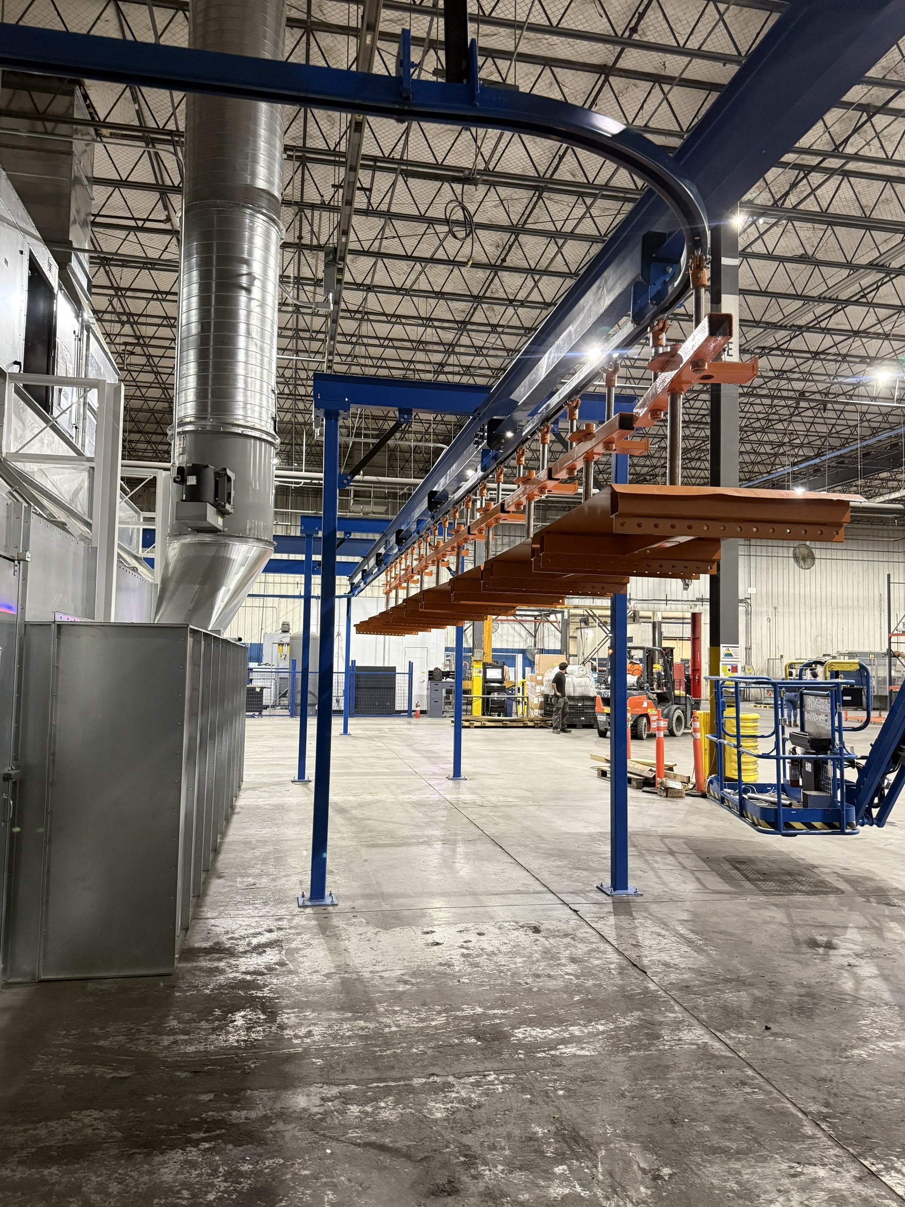 A row of orange carriers following the overhead route alongside the finishing enclosure.