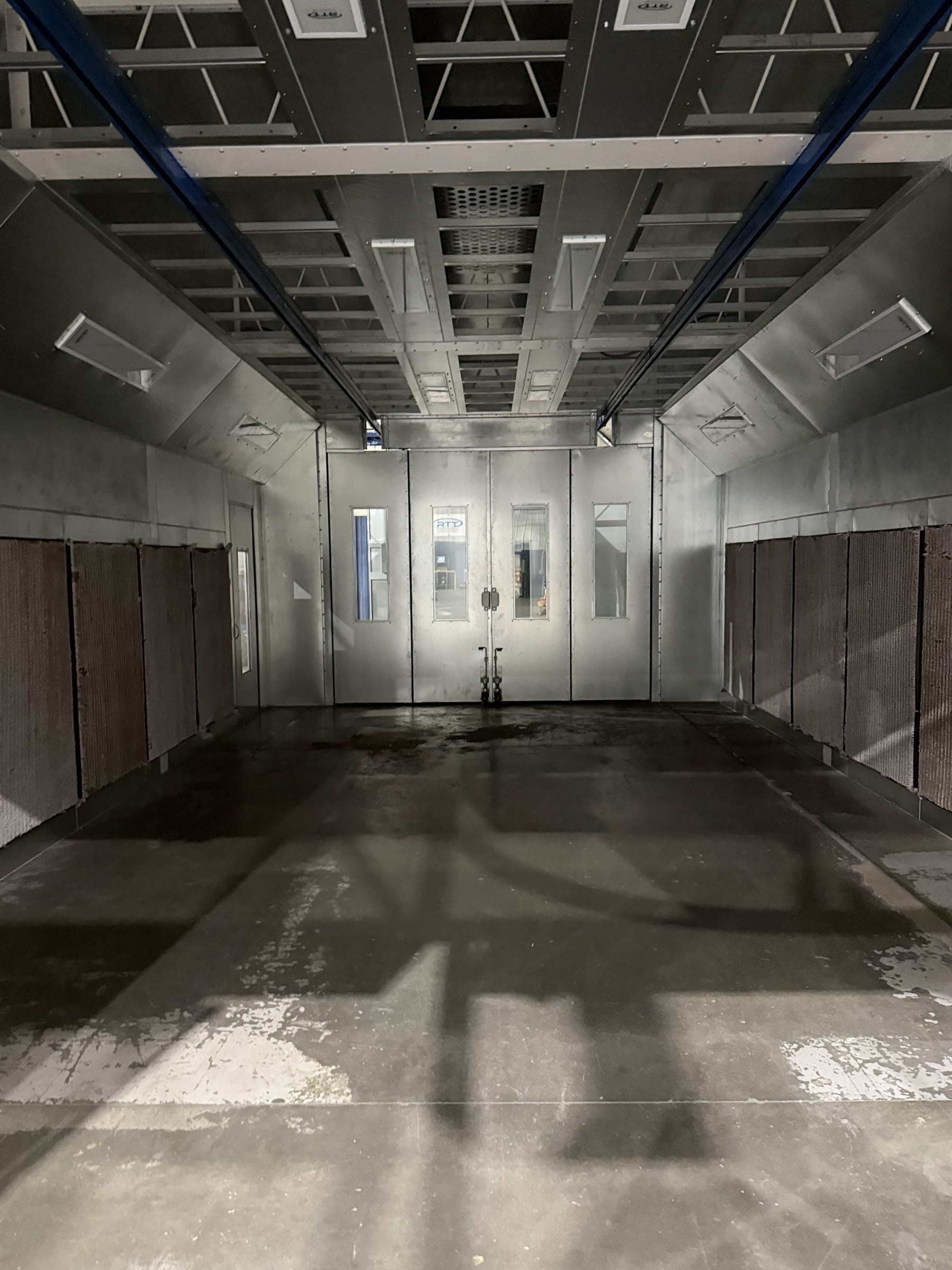 Interior view through the finishing enclosure beneath the overhead structure.