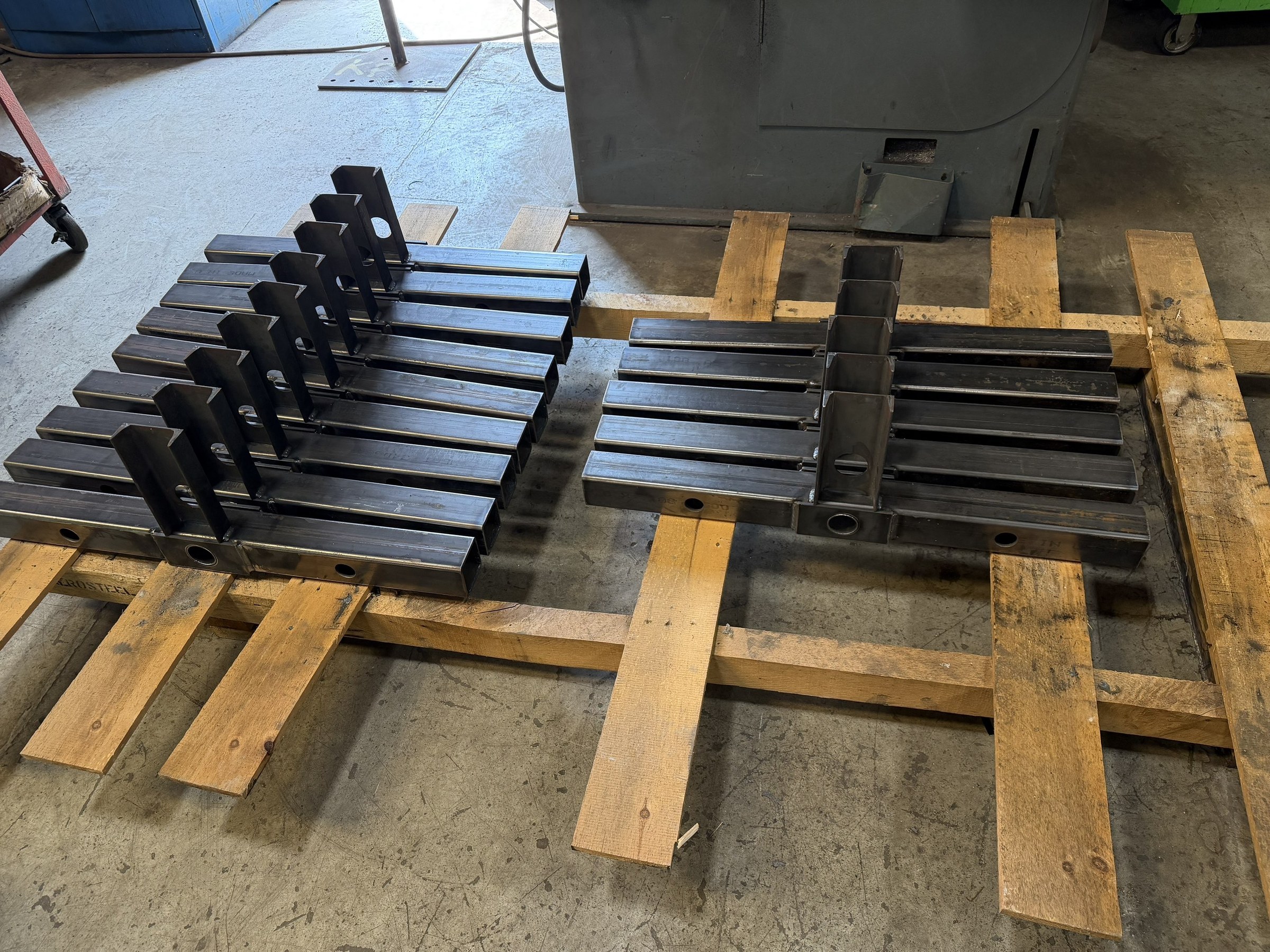 Repeated fabricated carrier components arranged on pallets.