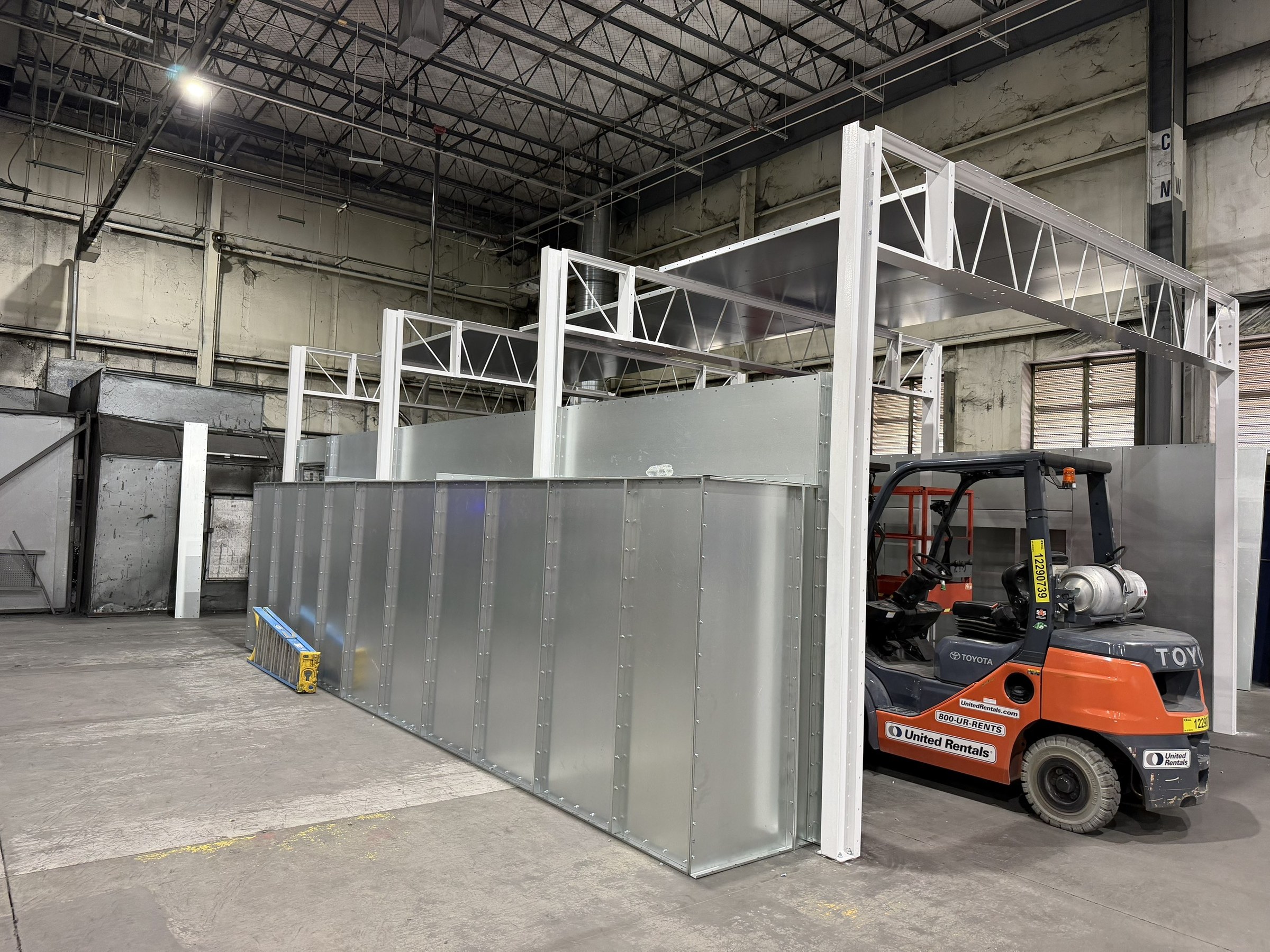 Booth wall panels and white framing during field assembly.