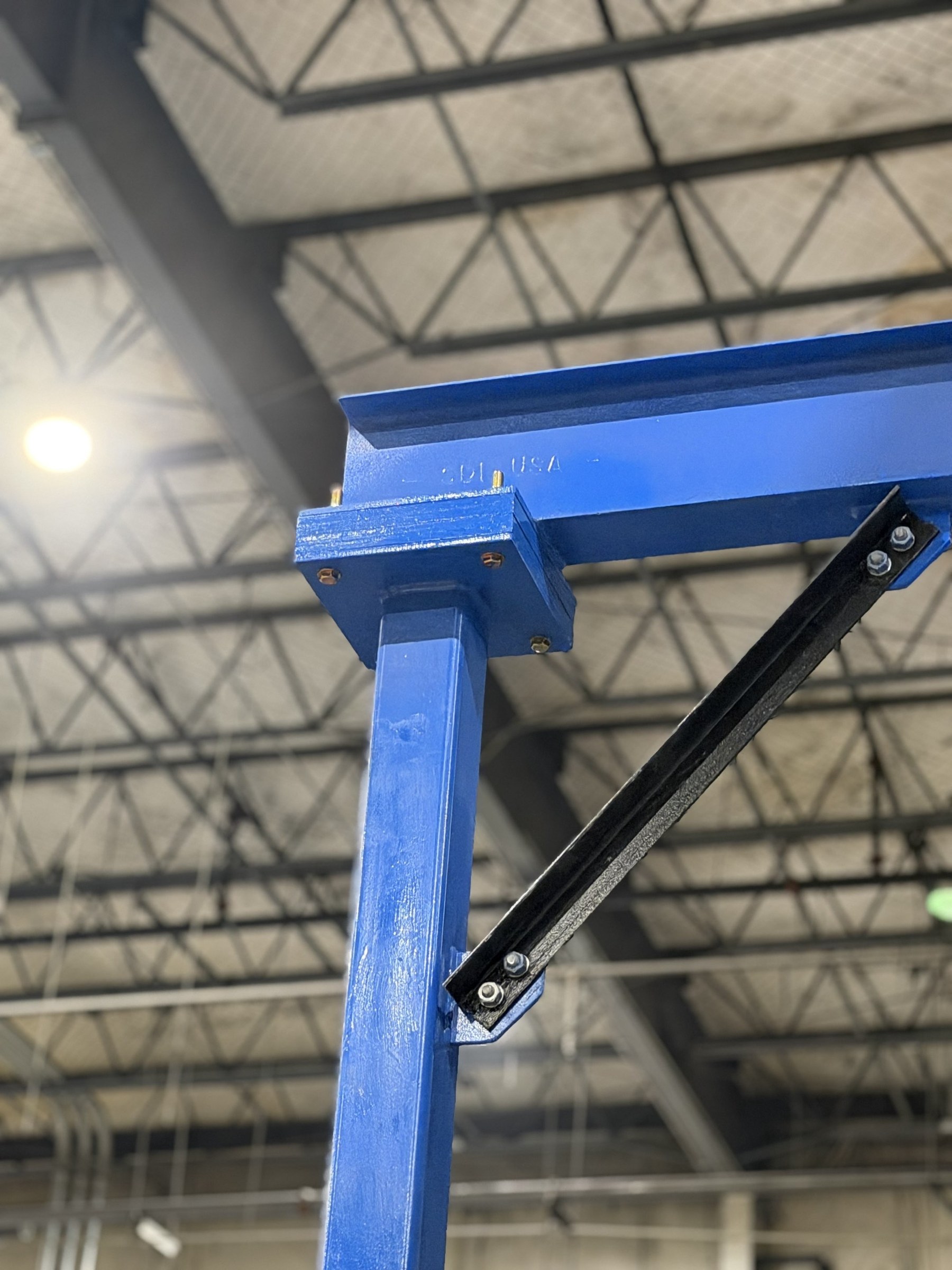 Close view of a bolted connection between a blue column and support beam.