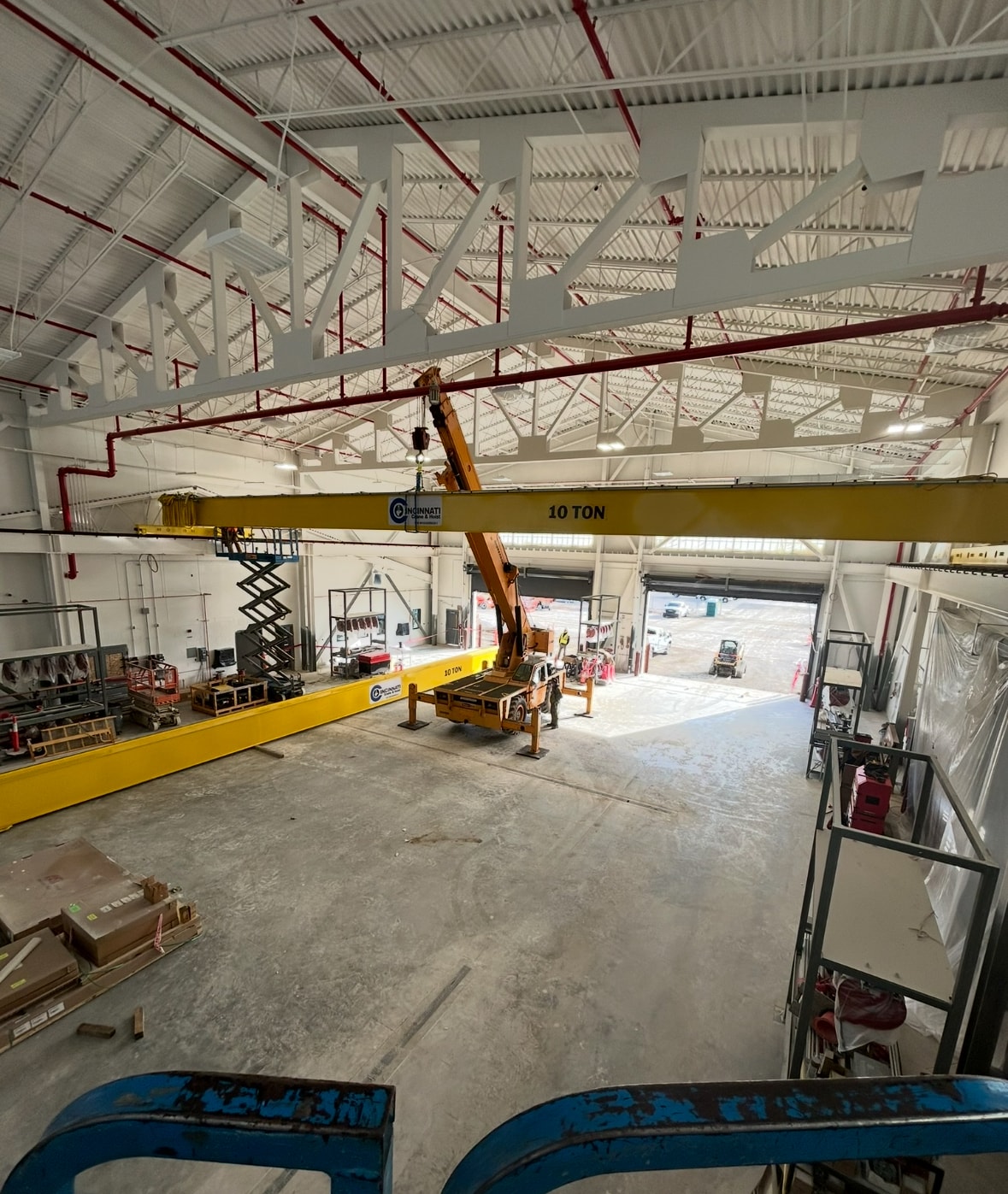 Installation: a mobile crane and elevated work platforms support bridge placement inside the Michigan facility.