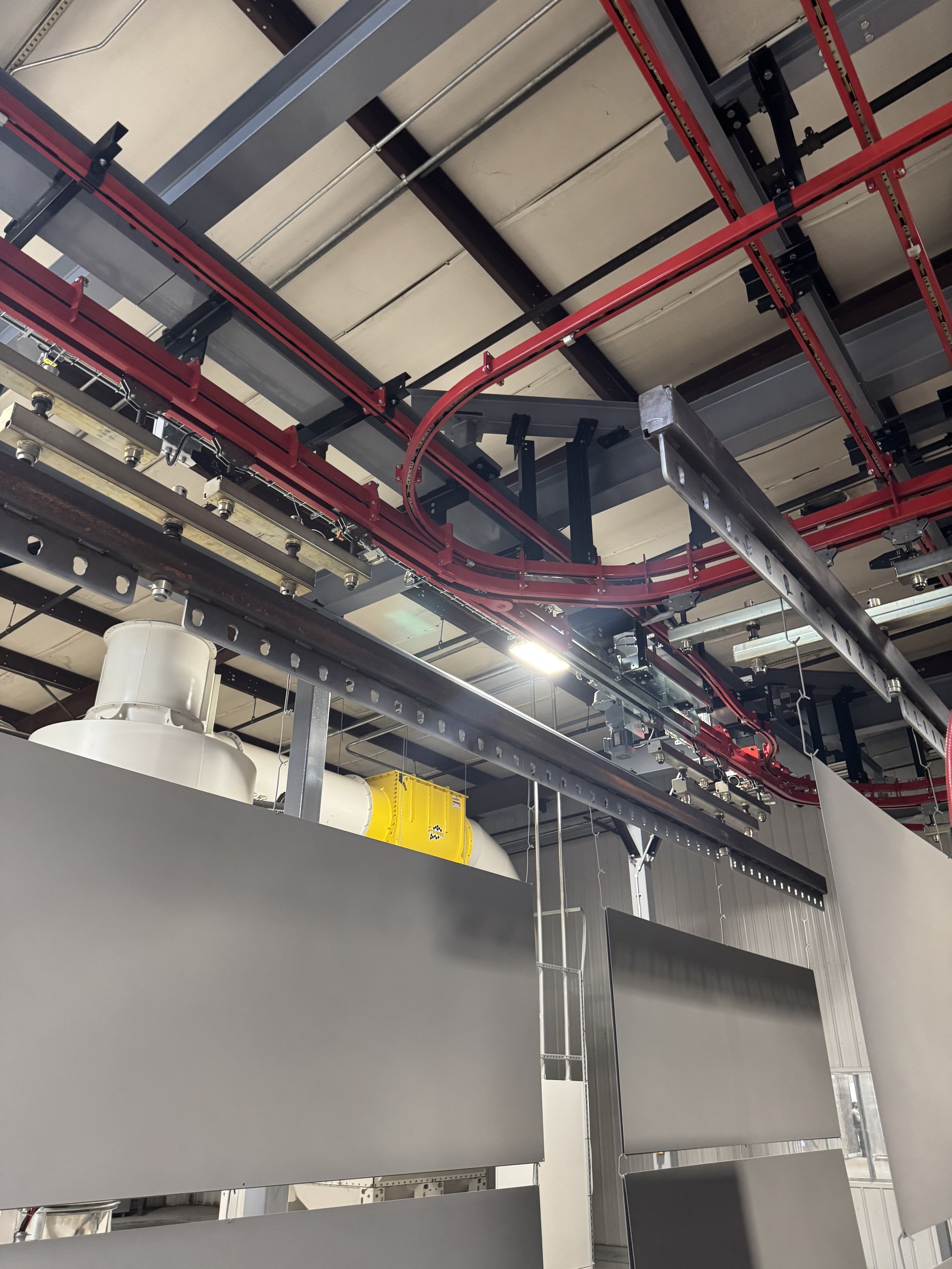 Track curves and carrier connections above suspended panels in the finishing area.