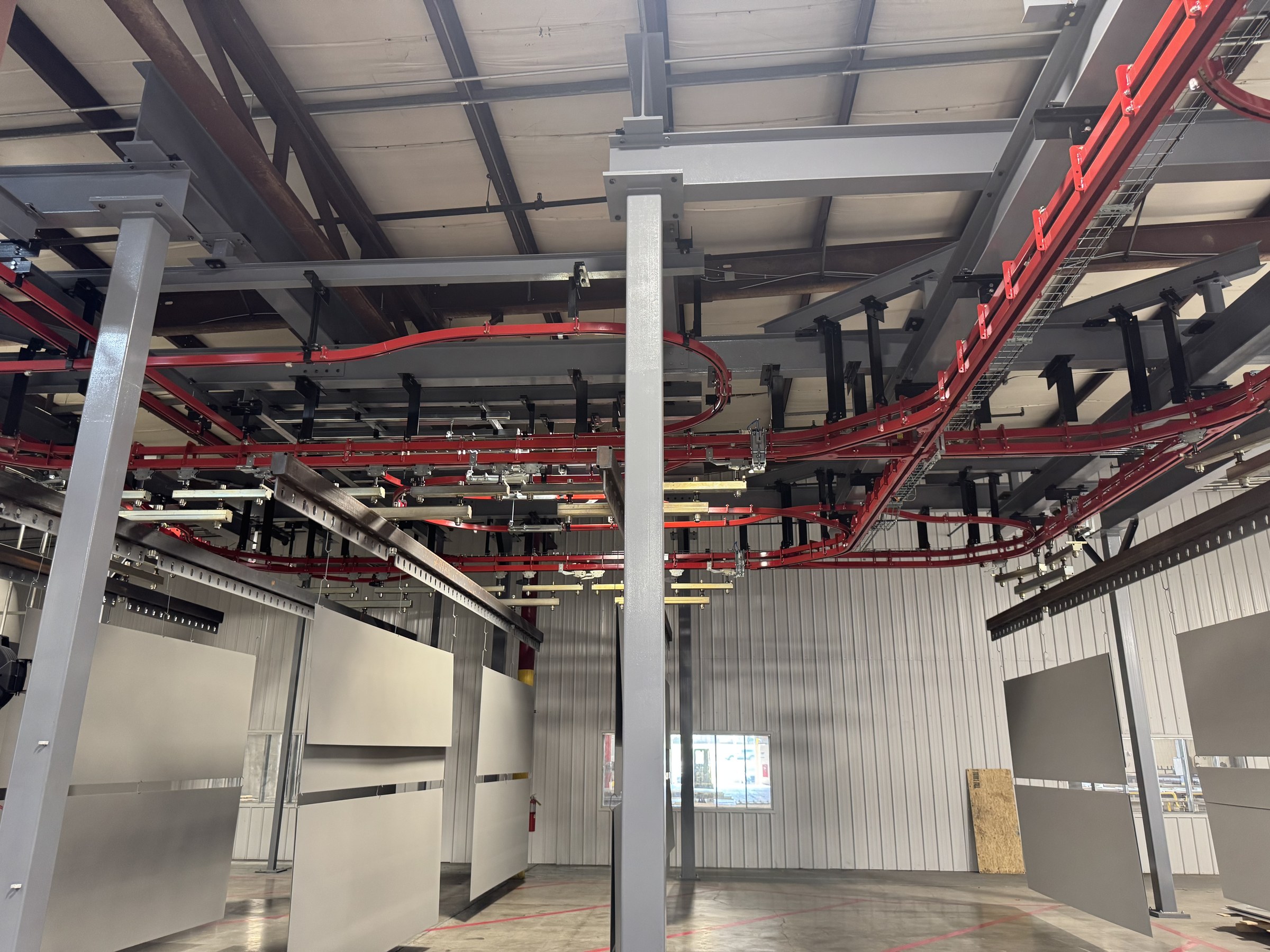 Conveyor routes arranged around the gray support frame above suspended panels.