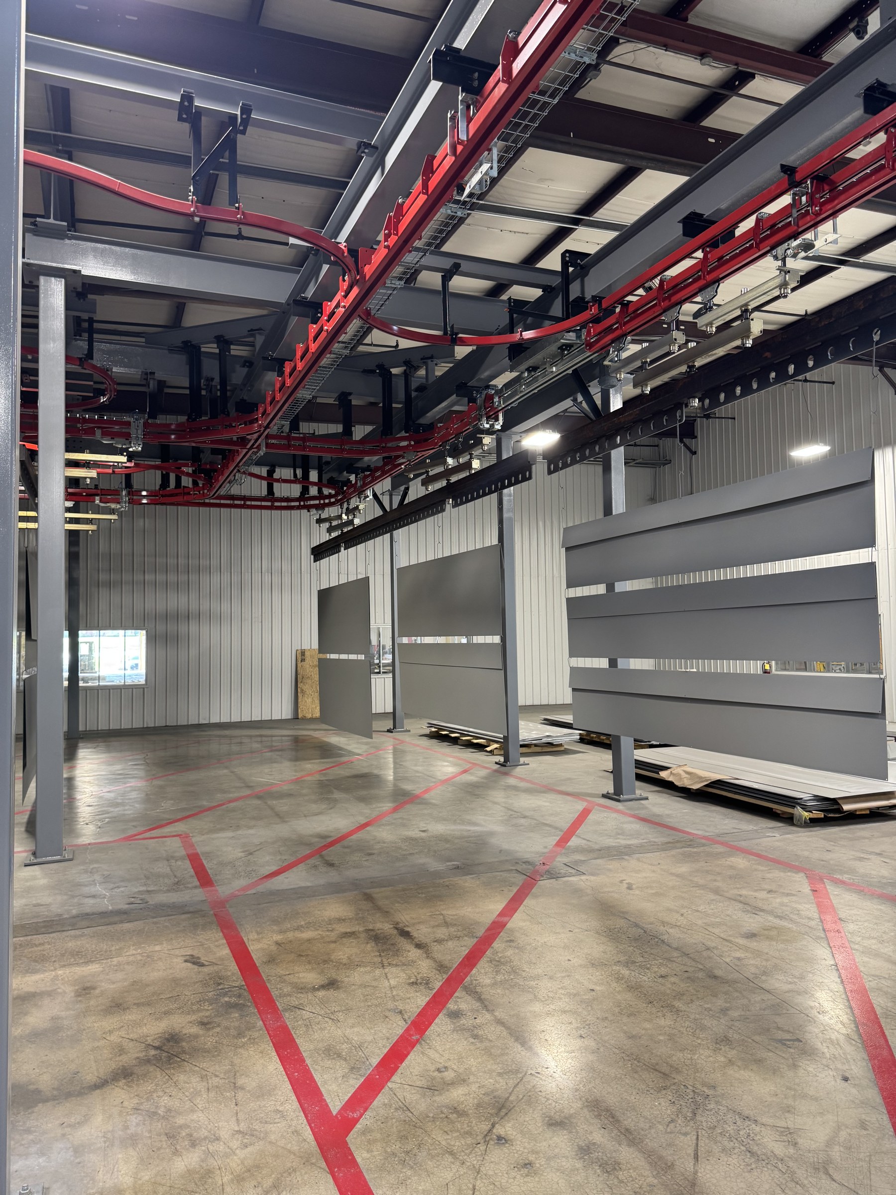 Parallel overhead routes and panel carriers alongside the marked floor area.