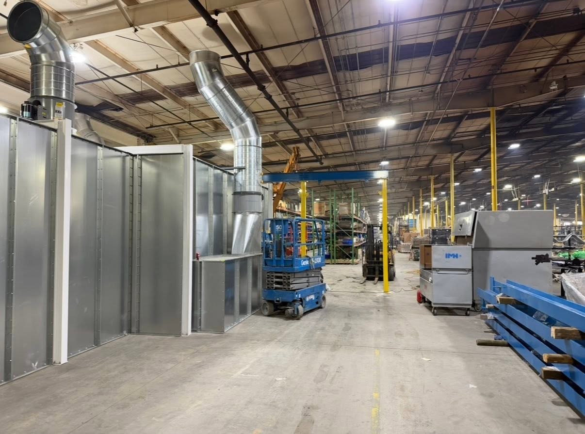 Partially assembled blue-and-yellow conveyor support structure beside the RTT paint equipment.