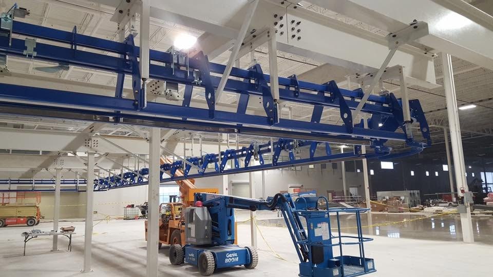 Curved blue conveyor rails suspended from the white support frame in Toledo.