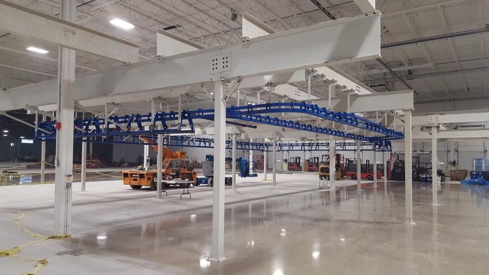 Blue power-and-free conveyor track on white supporting steel at the Toledo installation.