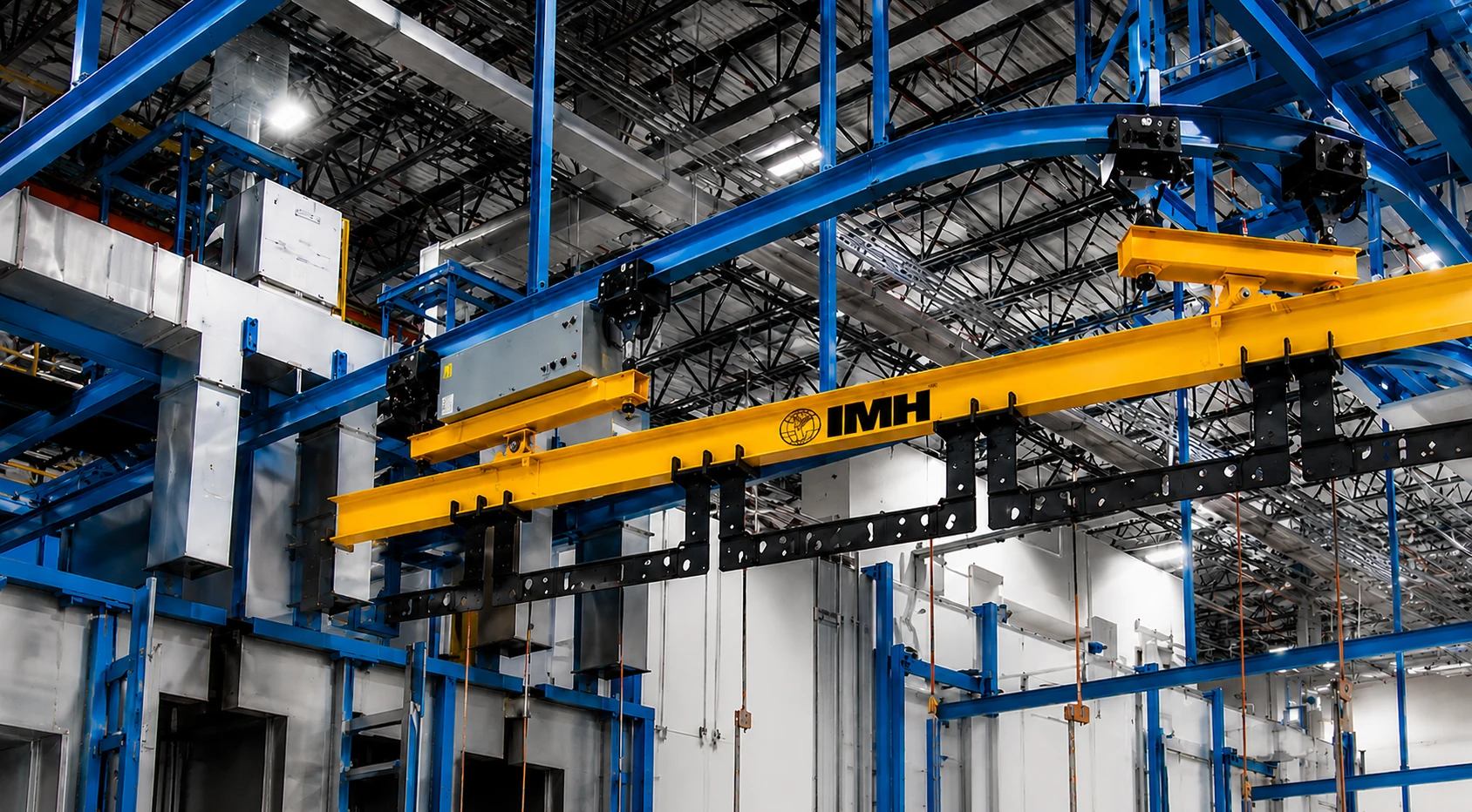Blue powered hoist monorail system with a yellow IMH lifting beam in an industrial facility