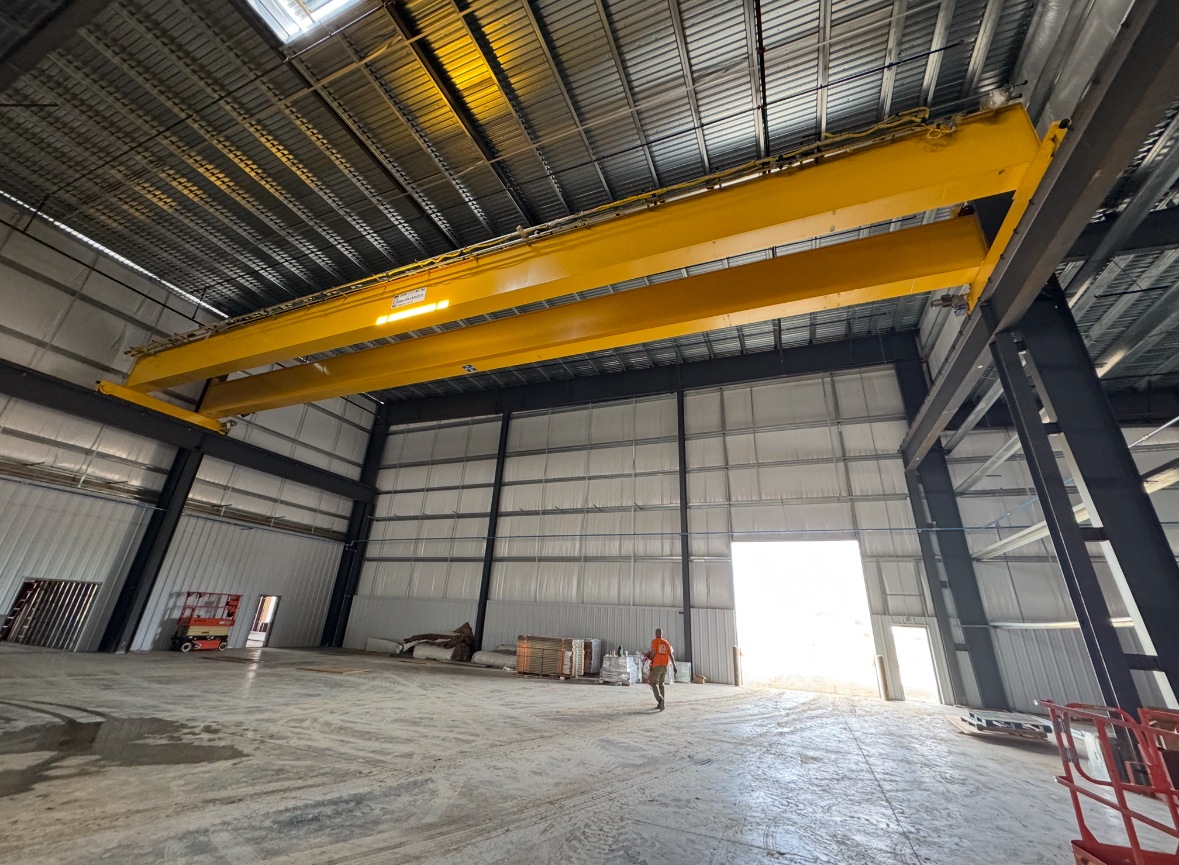 Yellow double-girder bridge crane above the runway beams and steel columns of the 40-ton crane installation.