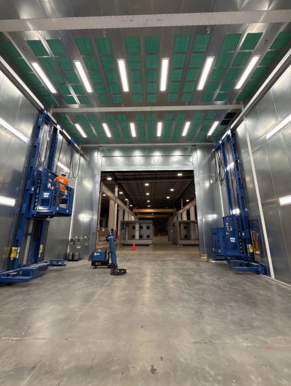 IMH booth installation with blue personnel platforms, overhead lighting, and green ceiling filter panels