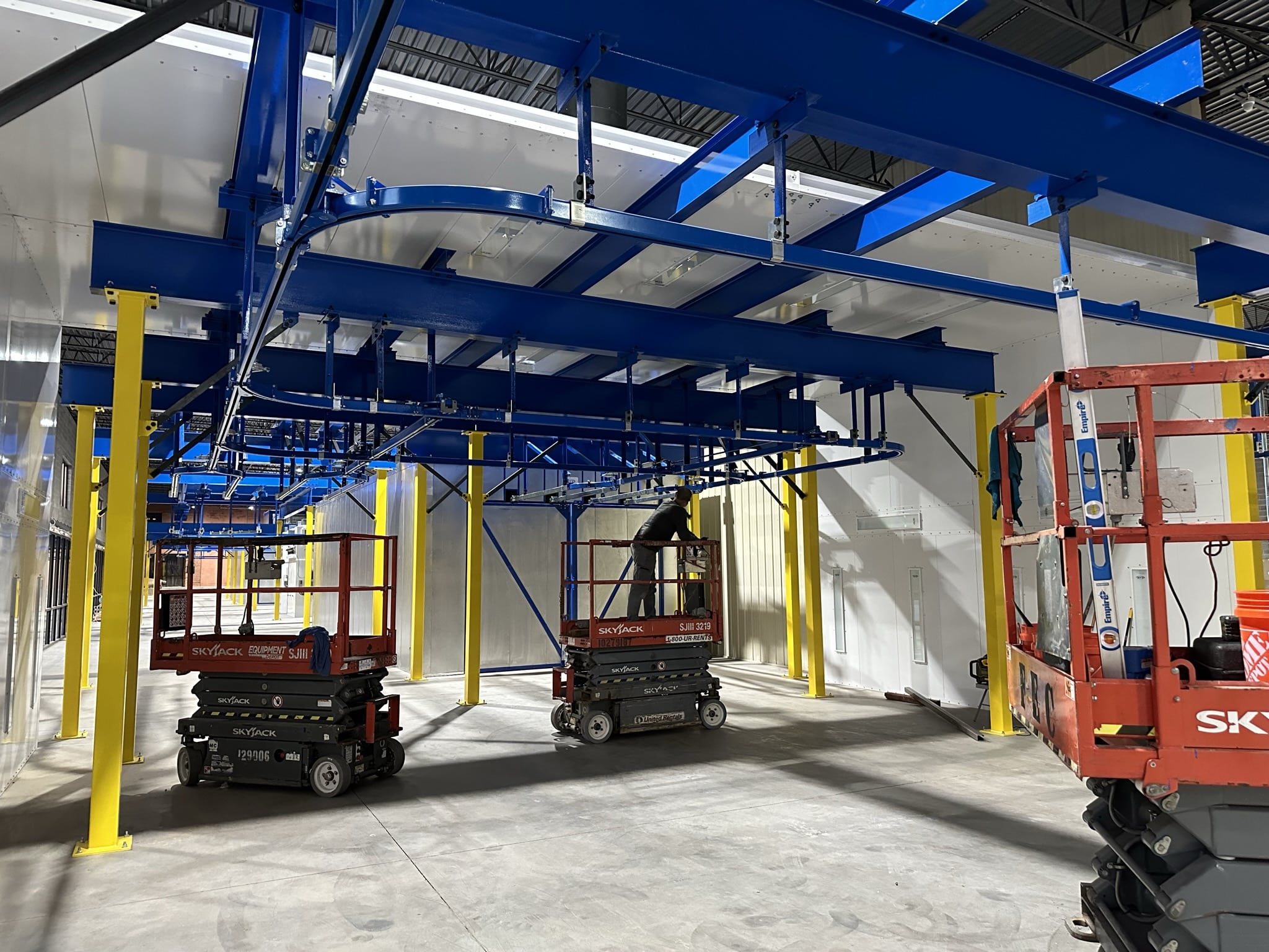 IMH crew installing a blue overhead conveyor system