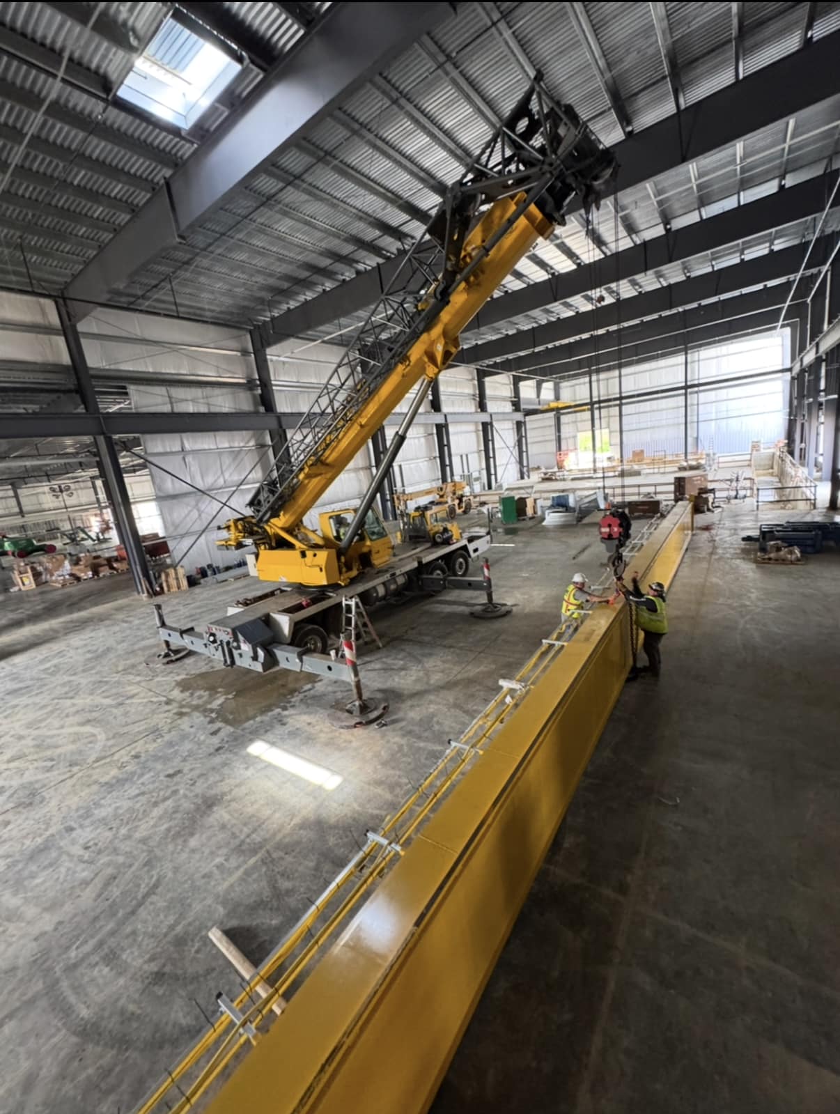 Bridge crane installation with yellow girders and mobile crane