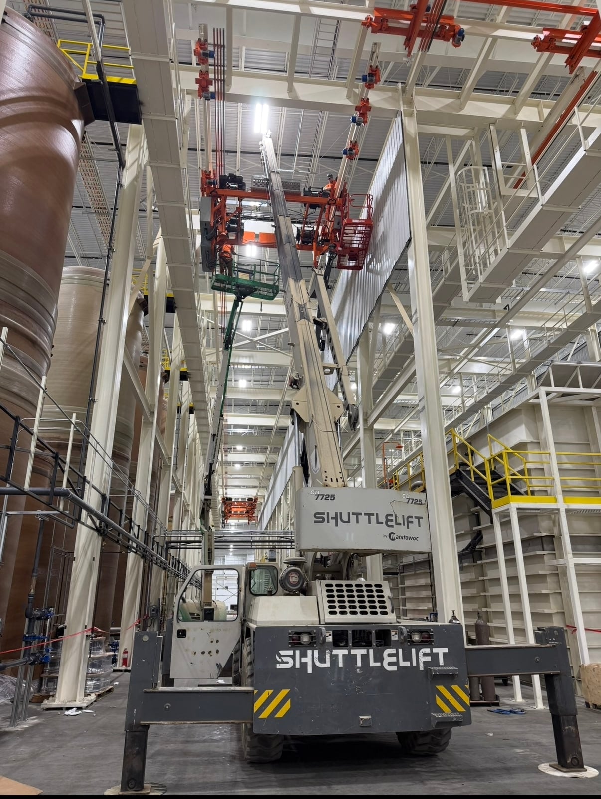 Industrial field crew installing an overhead conveyor with a scissor lift