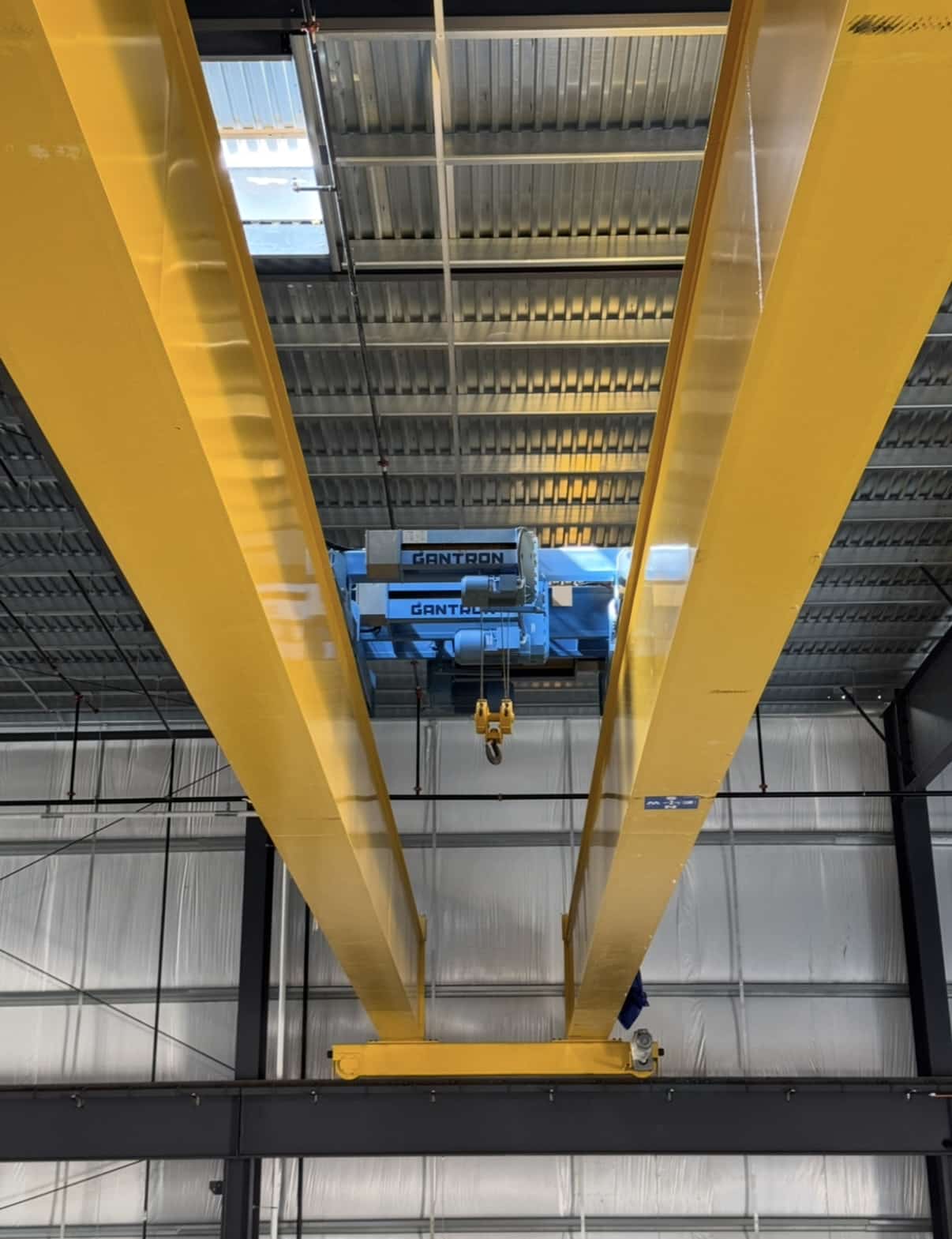 Top-running bridge crane with yellow girders and blue hoist