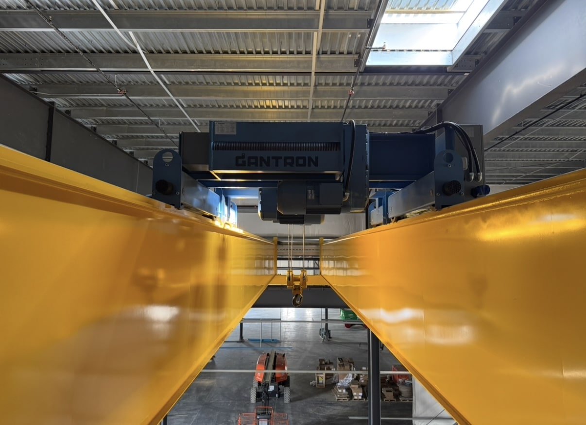 Industrial conveyor maintenance work with scissor lift and overhead equipment