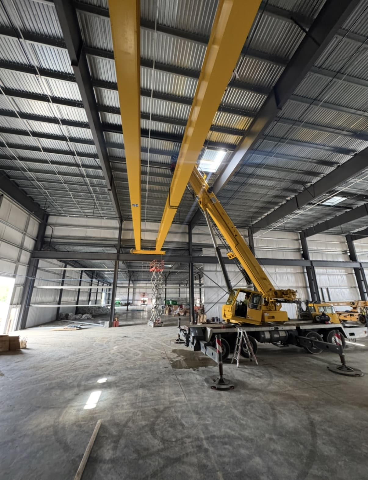 Industrial bridge crane installation with mobile crane and yellow girders