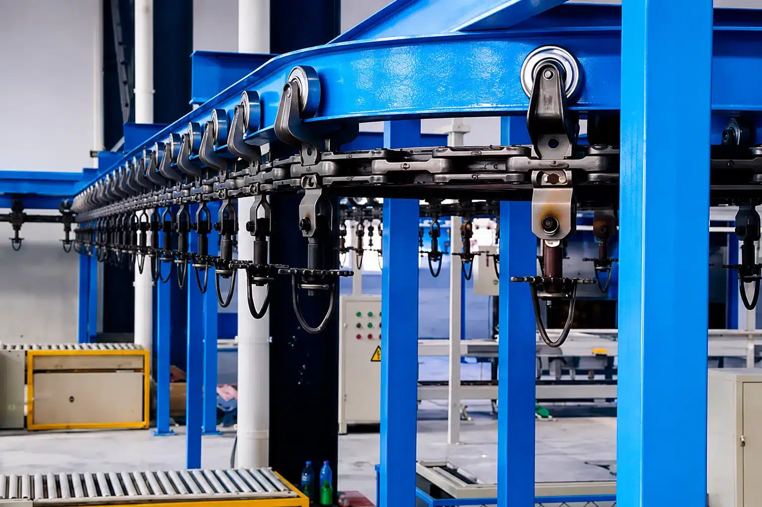 I-beam overhead conveyor system with trolley chain in an industrial facility